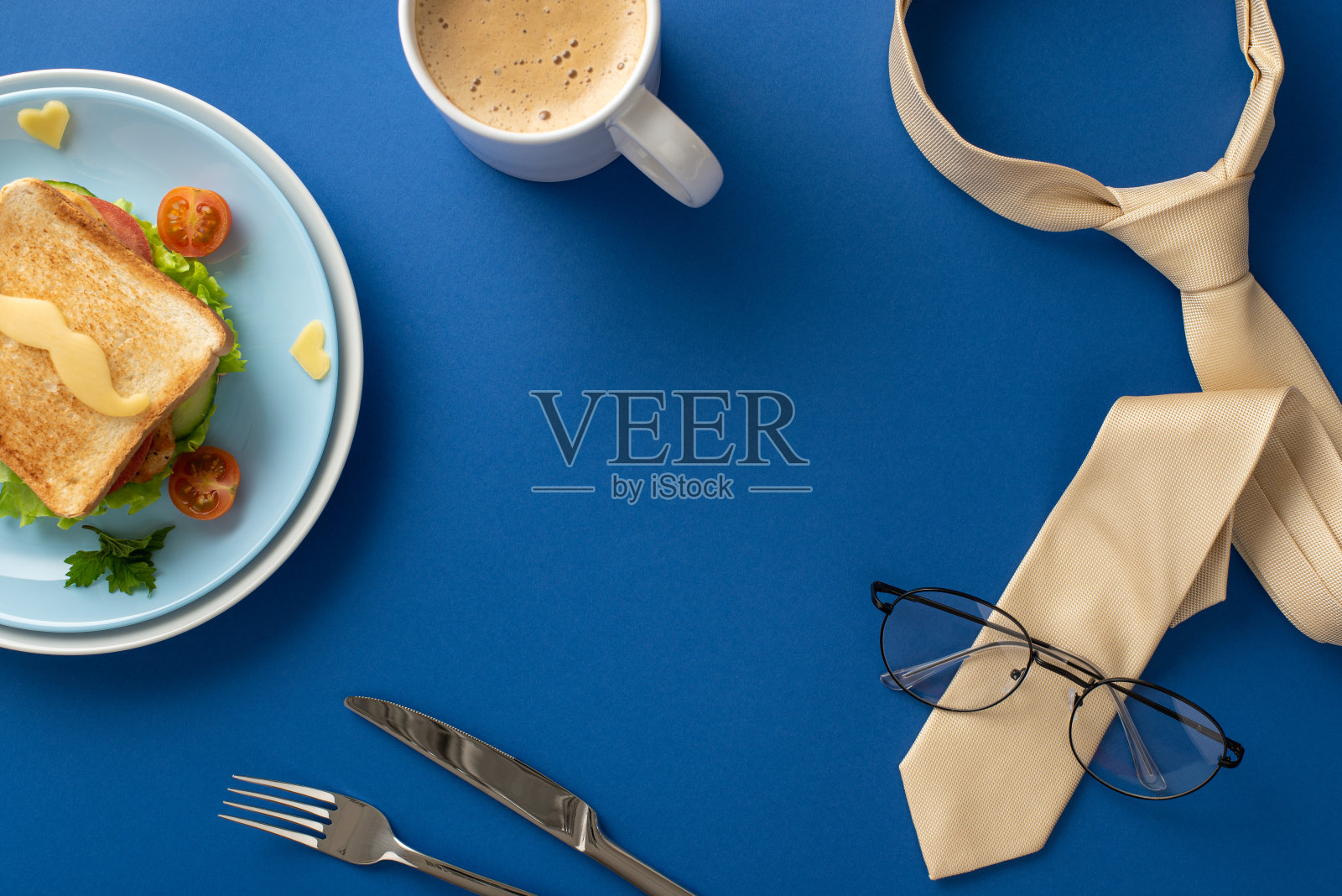 在父亲节,精心准备的早餐给爸爸留下深刻的印象!自制三明治的俯视图,胡子形状的奶酪,咖啡,领带,眼镜,蓝色背景与文字空间照片摄影图片