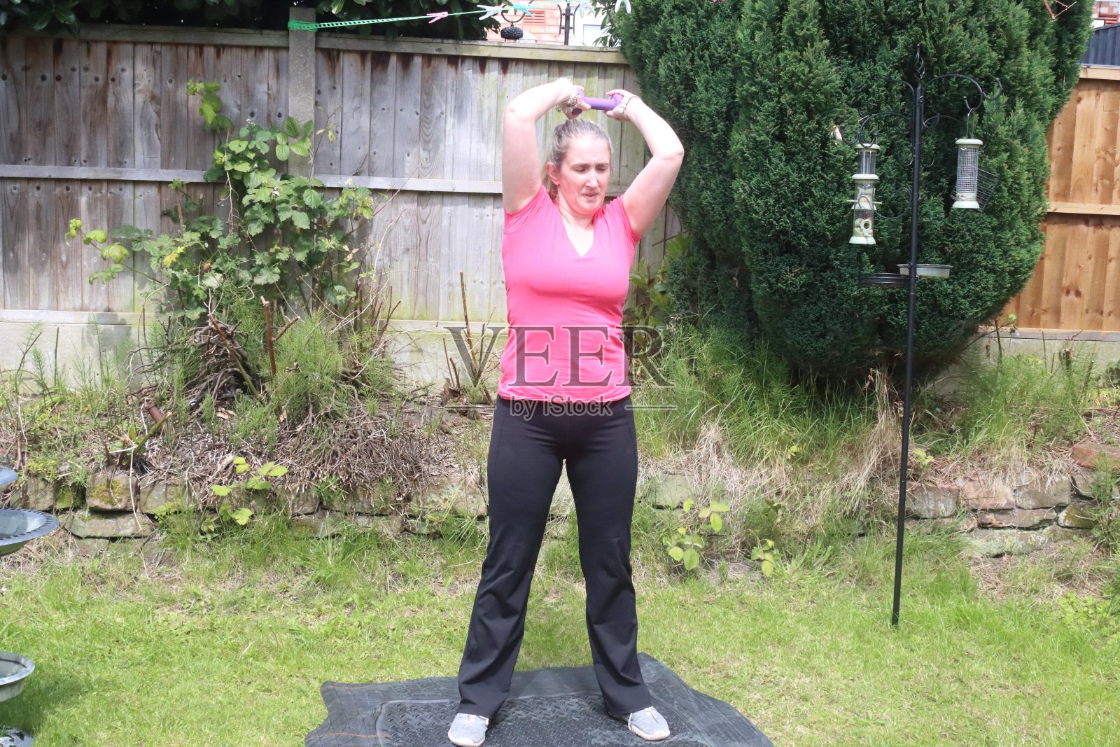 一张中年妇女在自家花园里做有氧和无氧混合运动的照片照片摄影图片