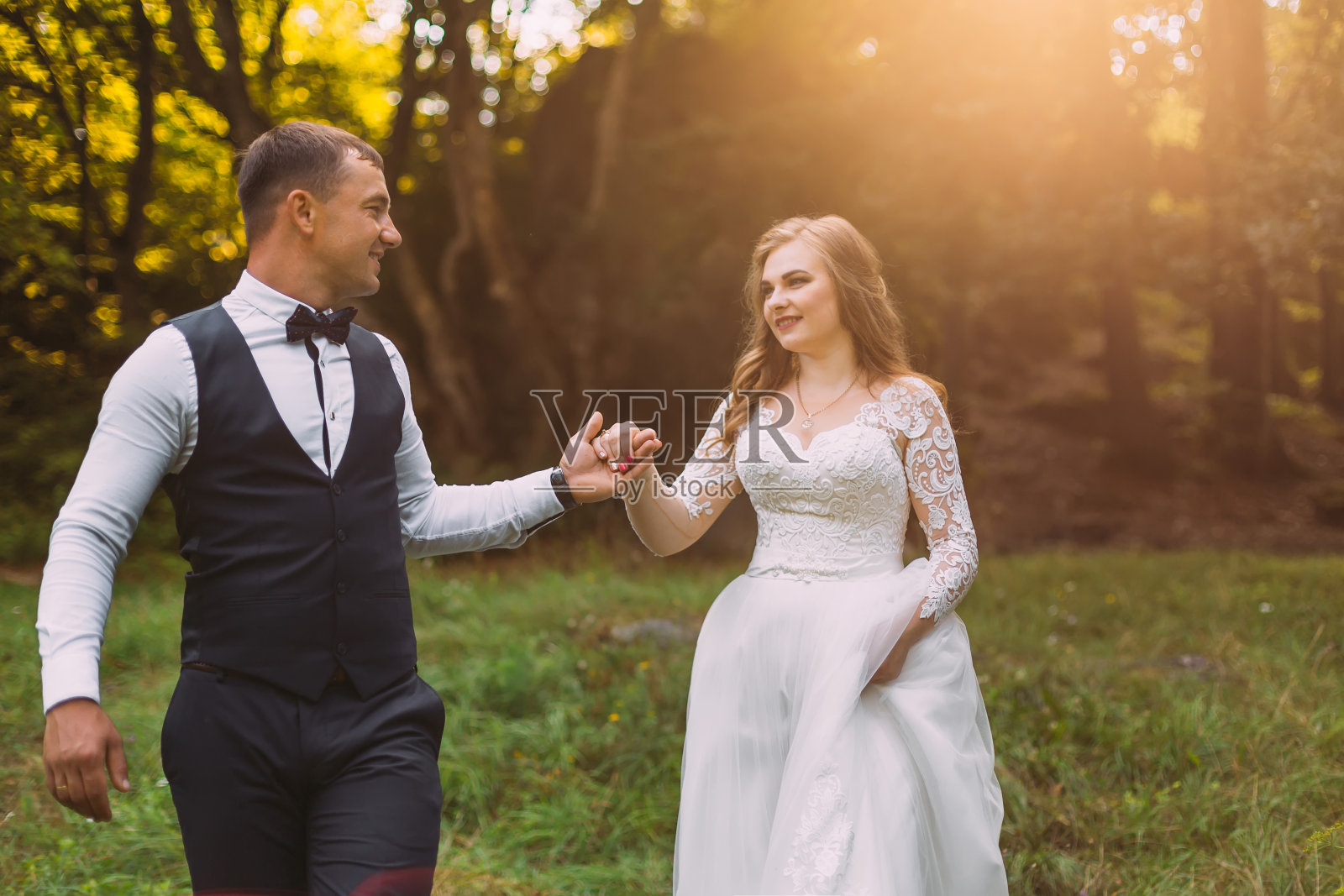 新娘穿着漂亮的蕾丝礼服,新郎穿着带b的马甲照片摄影图片