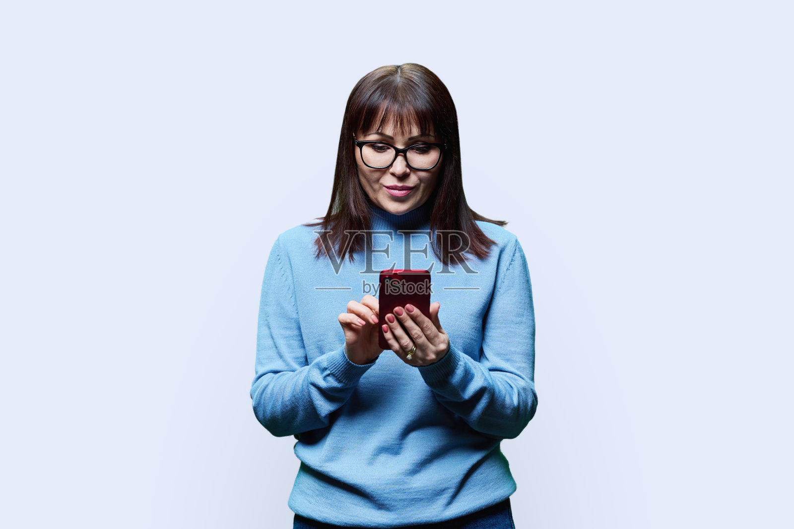 沉思的中年妇女在智能手机上阅读,白色背景照片摄影图片