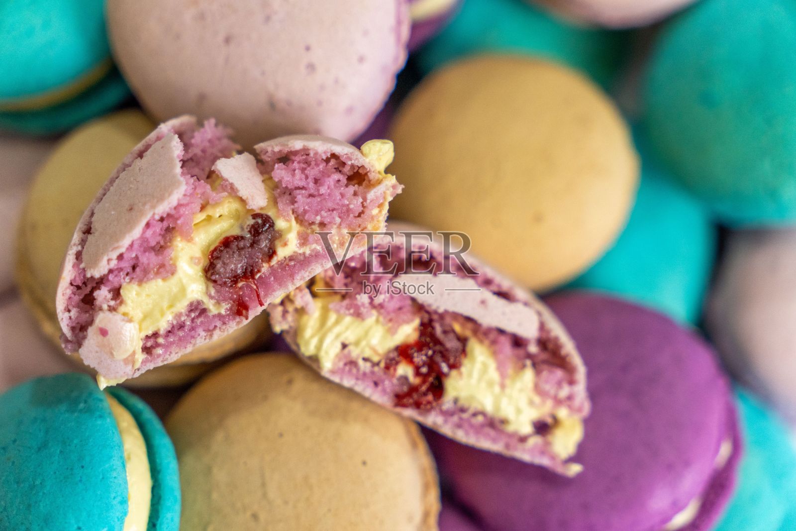 一系列烘烤马卡龙,有各种鲜艳的颜色,包括黄色和紫色照片摄影图片