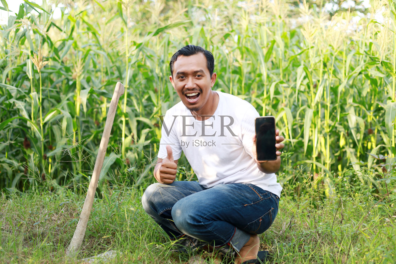 快乐的印尼农民站在种植园,显示空白的手机屏幕照片摄影图片