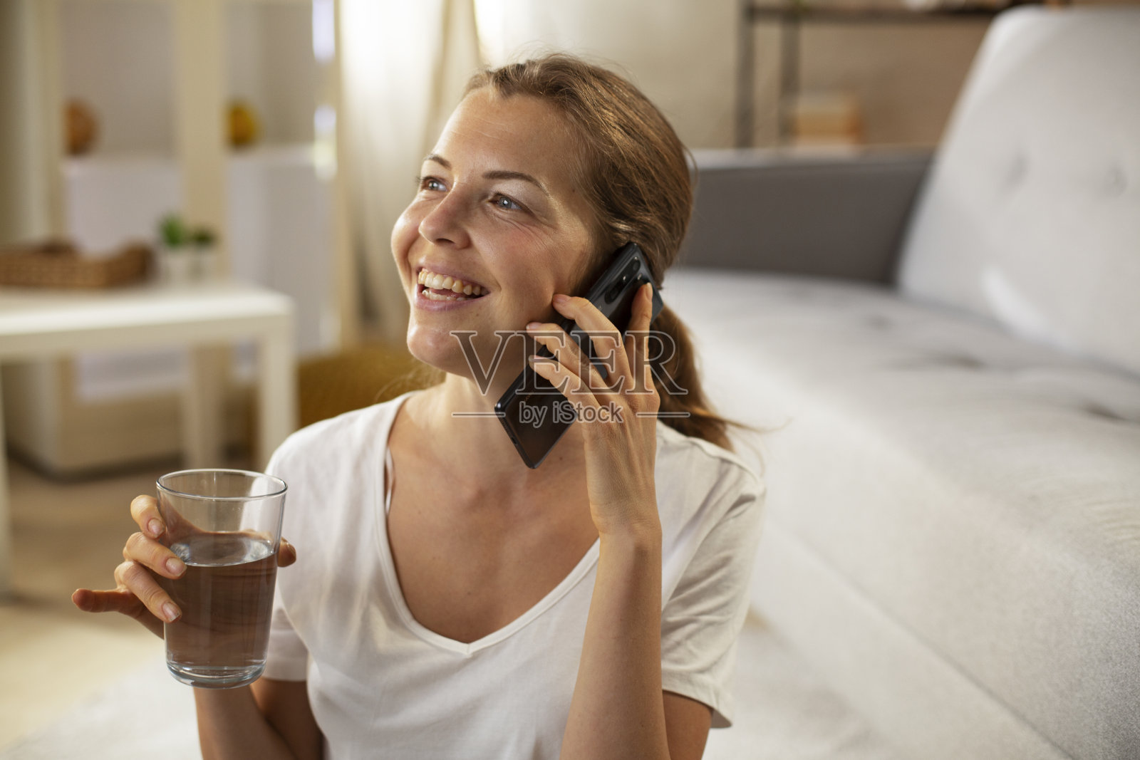 美丽的女人一边在家玩手机一边享受。照片摄影图片