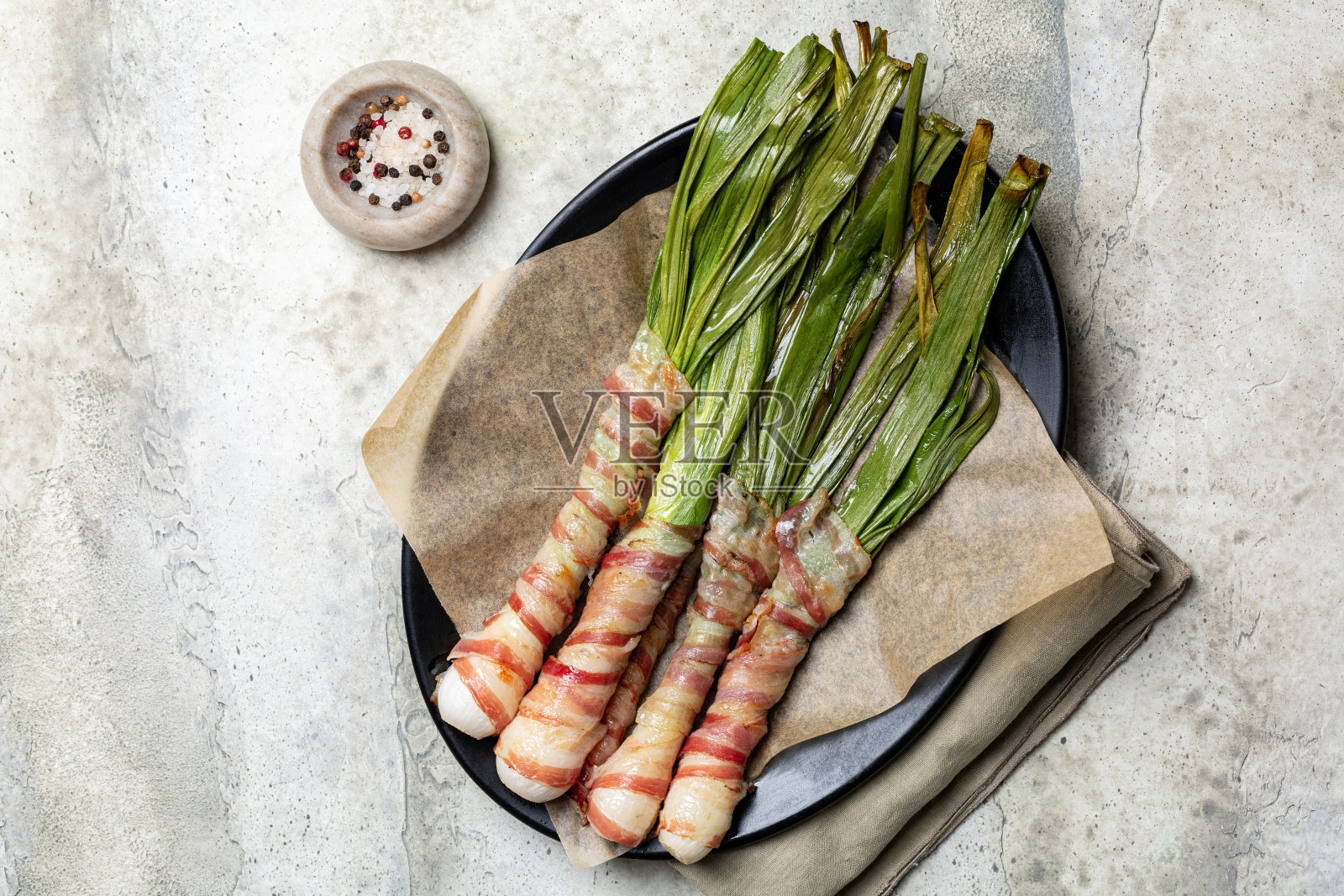 培根卷葱或小葱,在烤箱里烤,意大利菜称为cipollate con pancetta。前视图。照片摄影图片