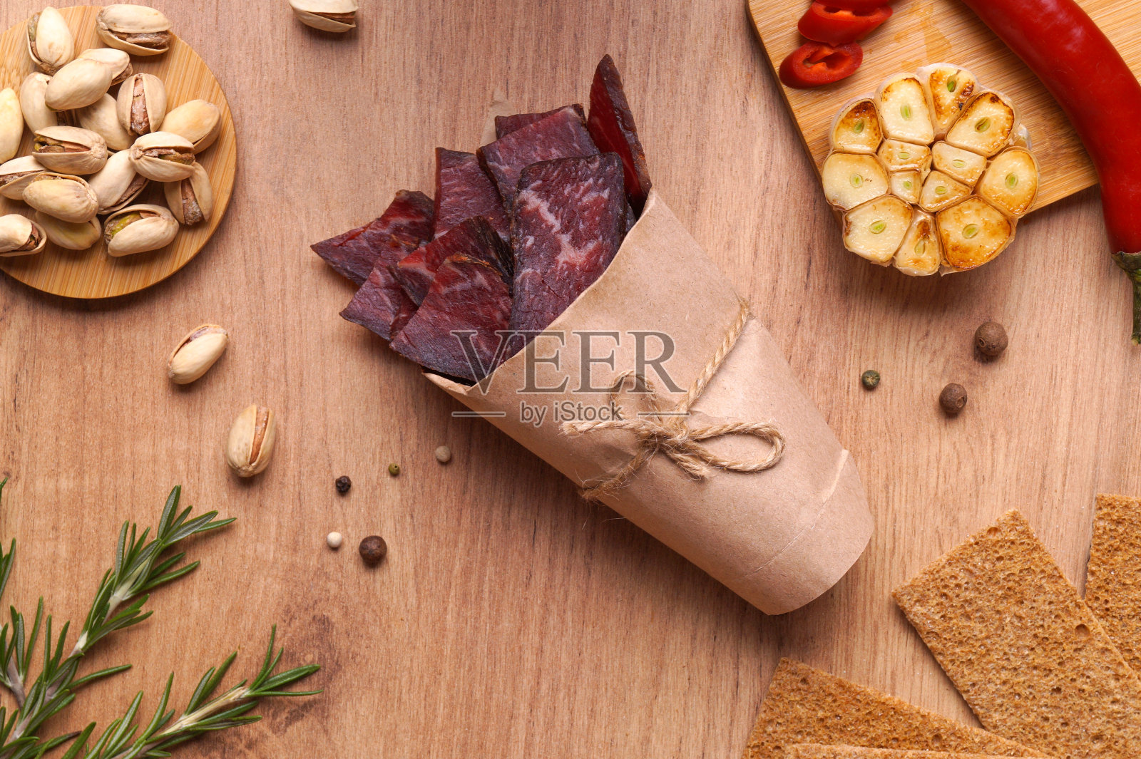 纸袋里装着一块块美味的牛肉干和不同的香料,平放在木桌上照片摄影图片