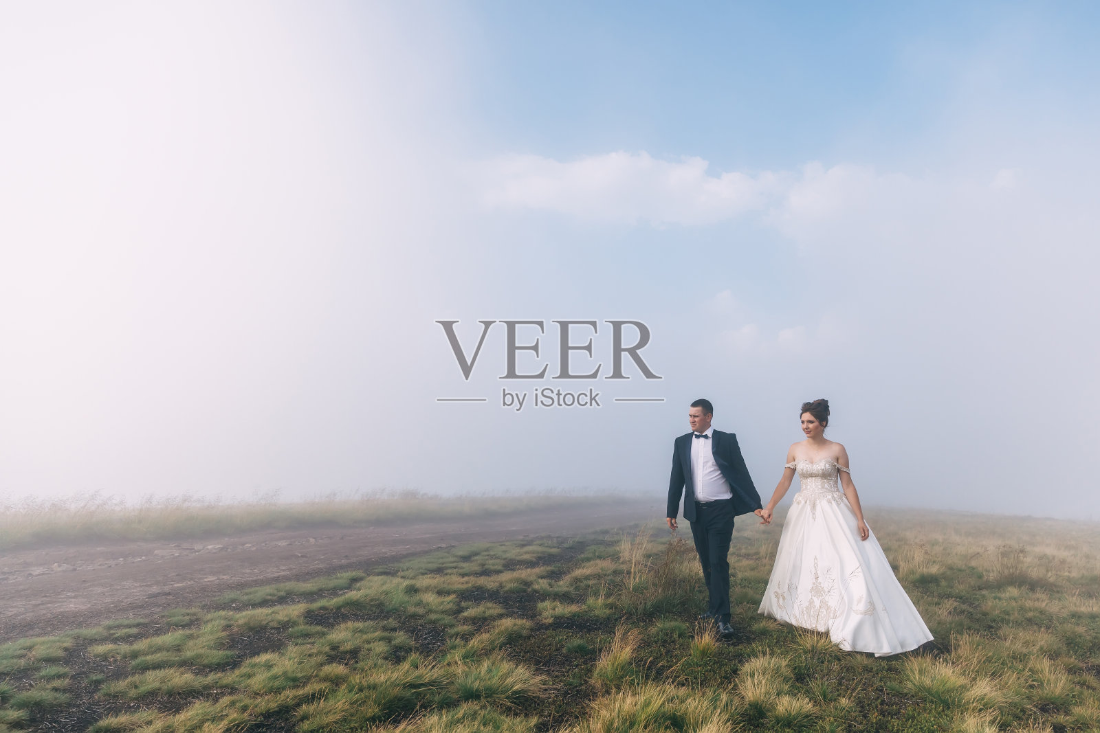 新郎新娘正在山间散步,大自然美得不可思议,浓雾弥漫。照片摄影图片