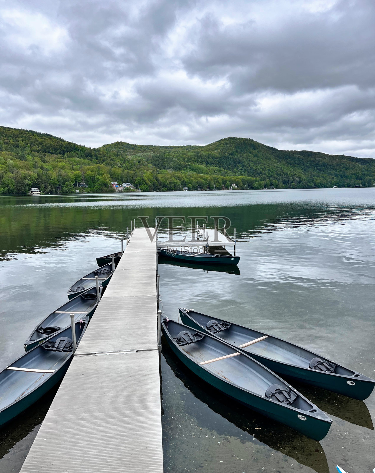 湖上有船的长码头(独木舟和皮划艇的码头,有山景和黑暗多云的天空)反射,划船照片摄影图片