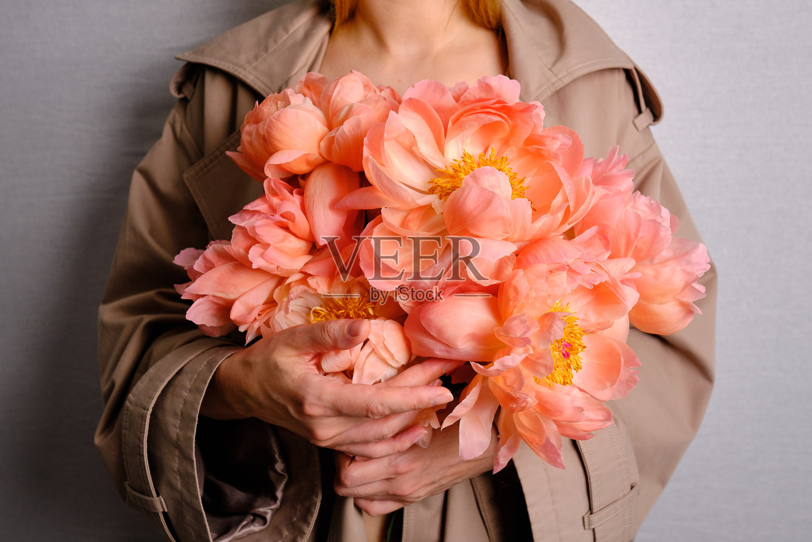 快乐的女人手里拿着粉红色的牡丹。卖花的女孩收集了一束牡丹。娇嫩的花朵很美。一份节日礼物,春天心情。浪漫的惊喜照片摄影图片