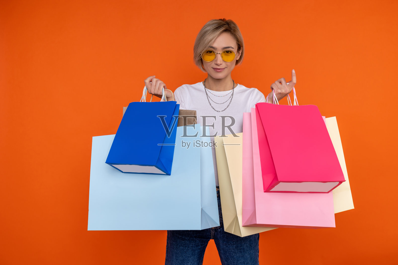 自信的女人穿着白t恤和牛仔裤,把买的东西装在袋子里,喜欢购物照片摄影图片