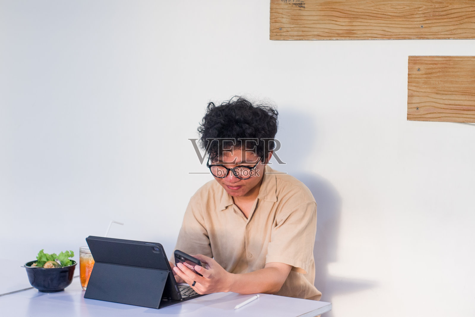 一头卷发的年轻亚洲男子坐在咖啡馆里使用电子设备工作照片摄影图片