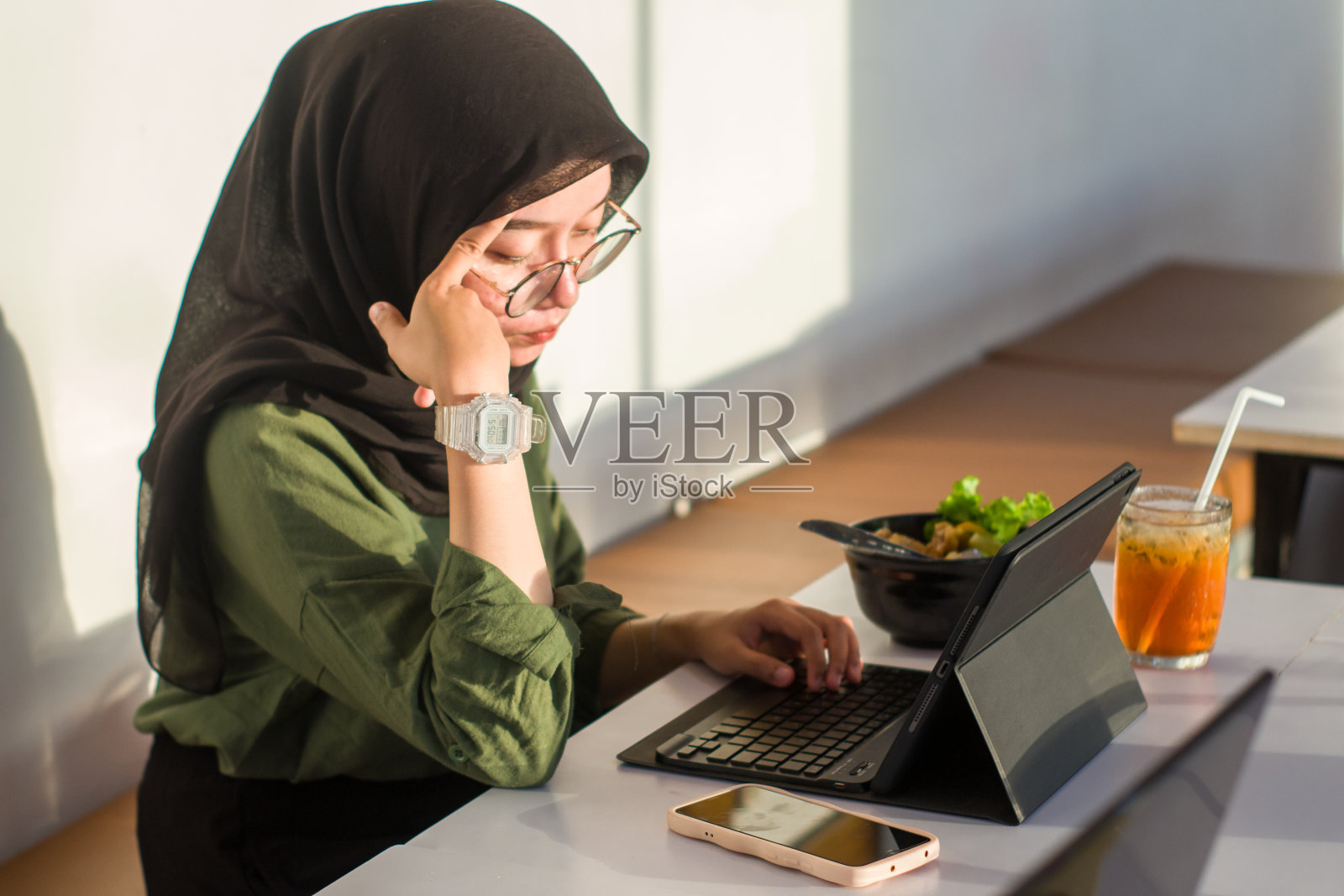 印度尼西亚年轻的穆斯林妇女坐在咖啡馆里使用数码平板电脑工作照片摄影图片