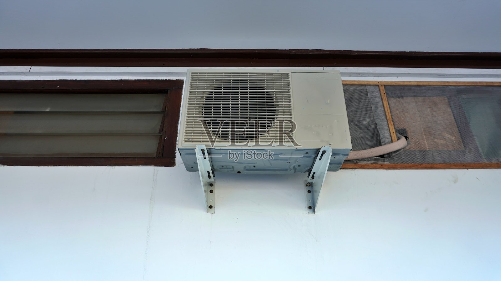 室外空调压缩机悬挂在建筑物靠近窗户和天花板的室外墙壁上照片摄影图片