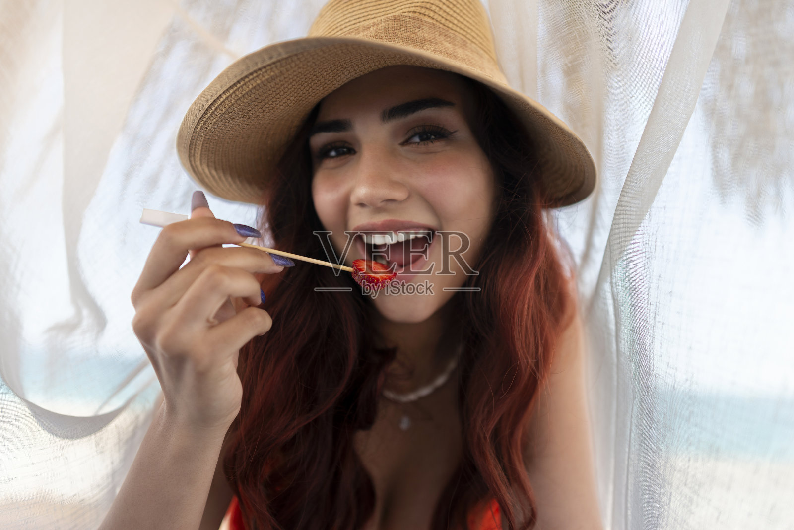 年轻女子吃草莓。照片摄影图片