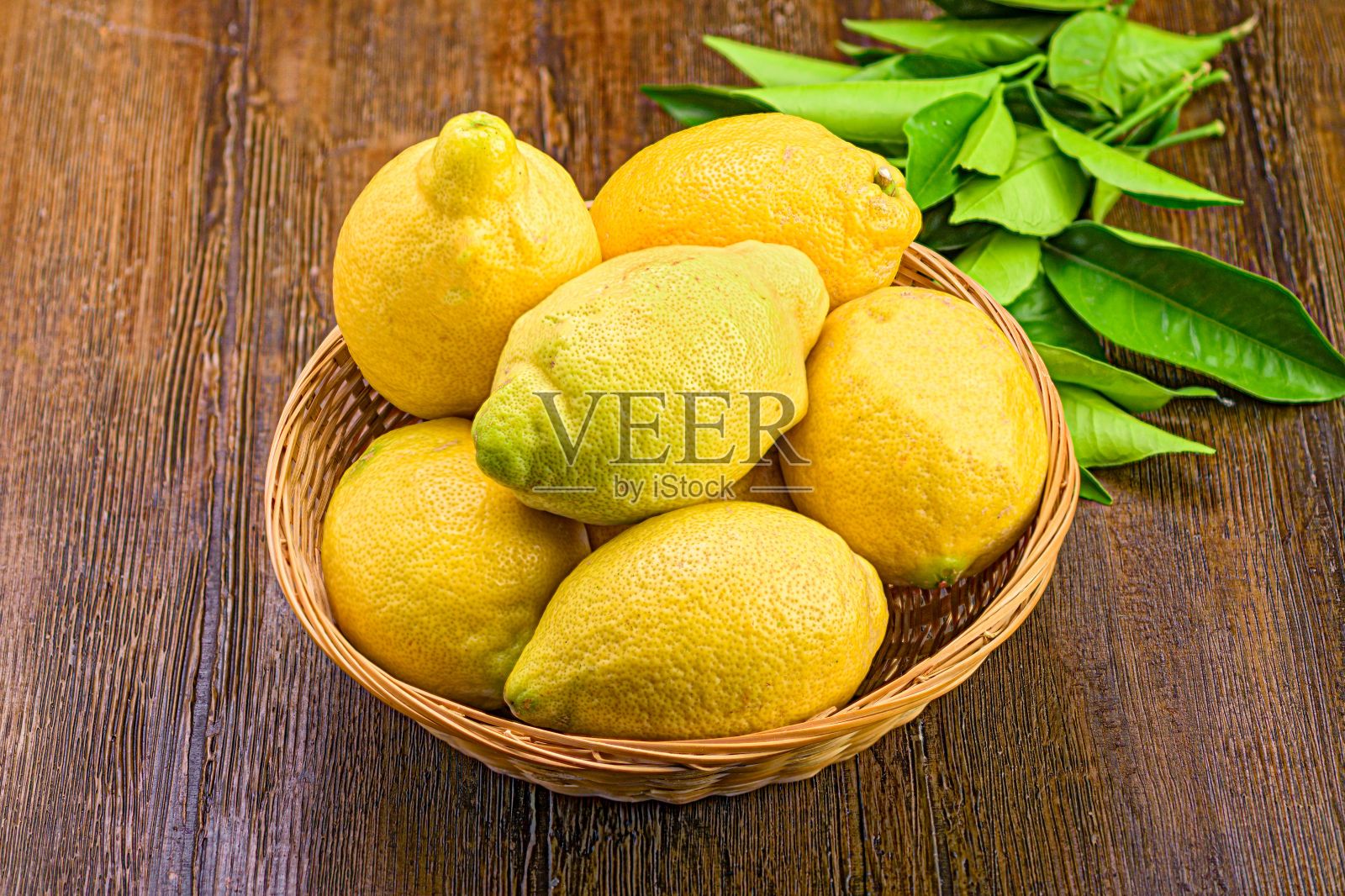木桌上摆着一个装满新鲜柠檬的篮子,给人一种明亮愉快的感觉照片摄影图片