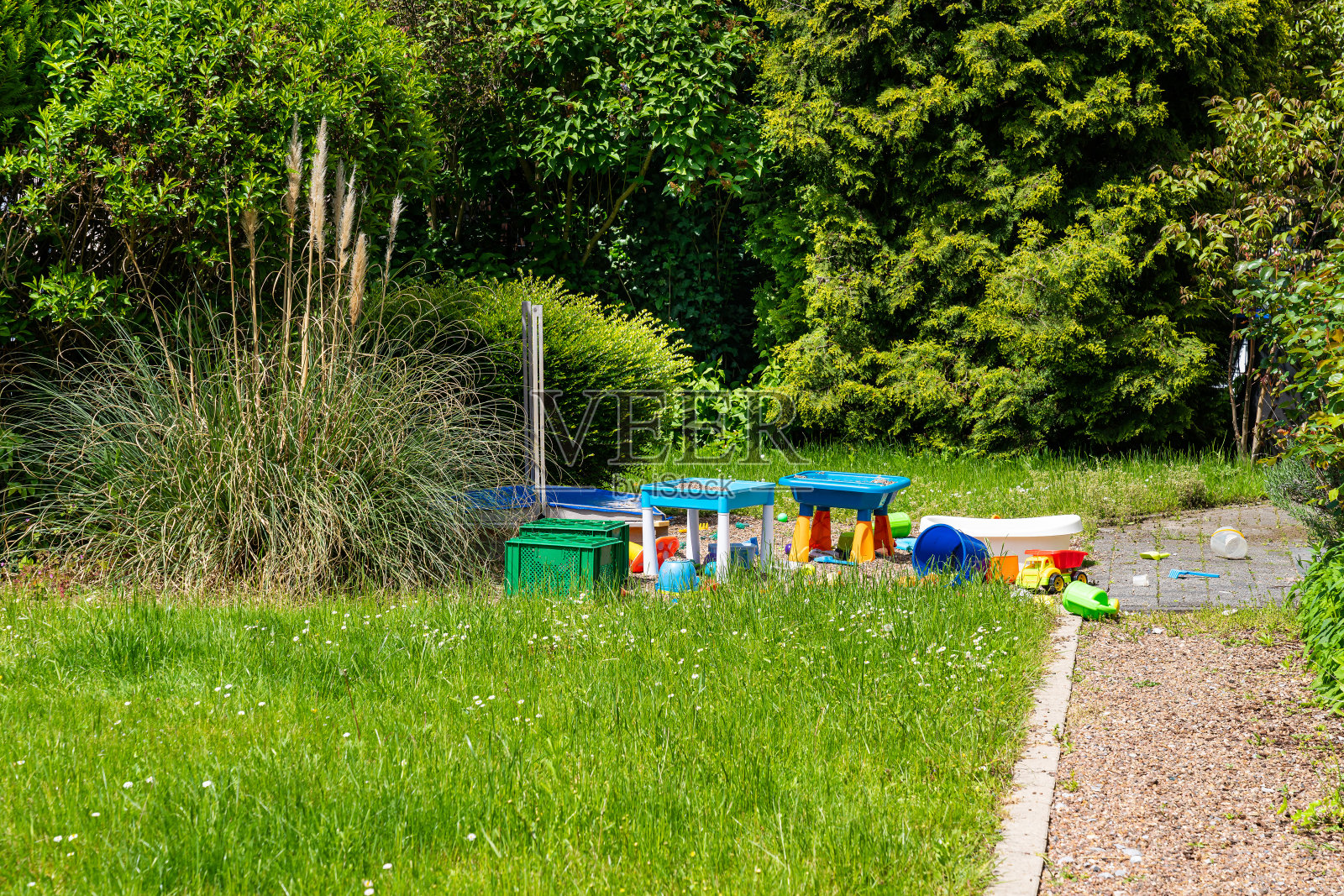 五颜六色的儿童塑料玩具散落在绿色的草坪上。照片摄影图片
