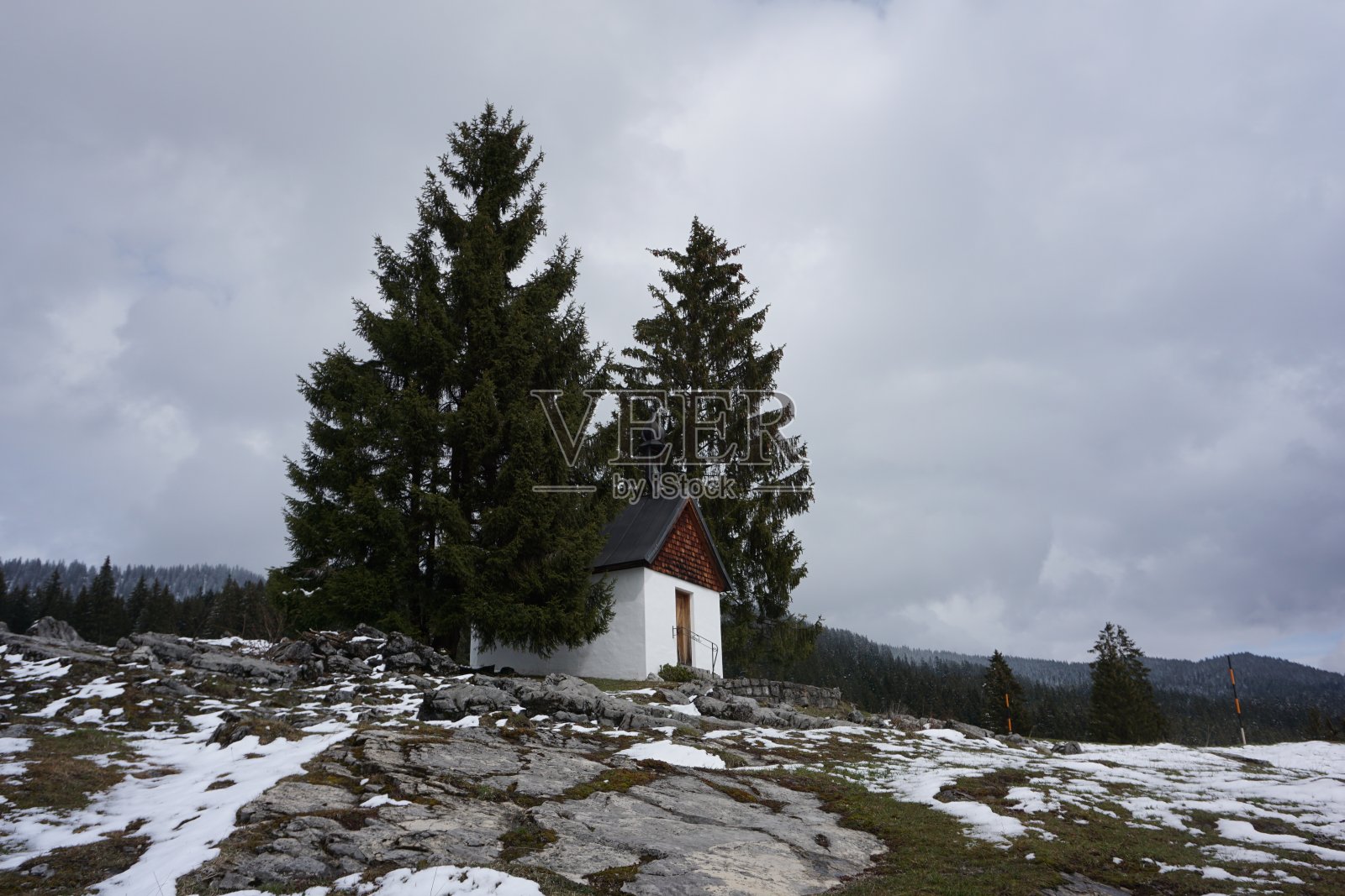 阿尔卑斯山上一条通往耶稣十字架的小径。宗教走。早春在巴伐利亚的散步。山上最后一场雪。通往教堂的小路。照片摄影图片