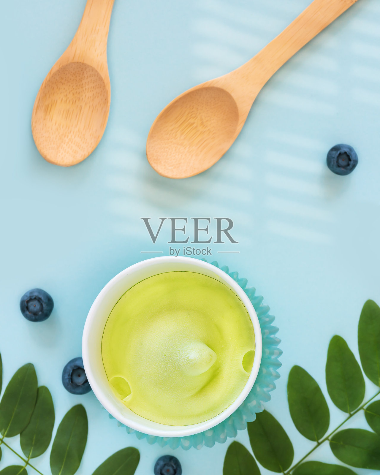 天然素食冰淇淋,蓝莓,树叶和木制勺子在蓝色的背景照片摄影图片