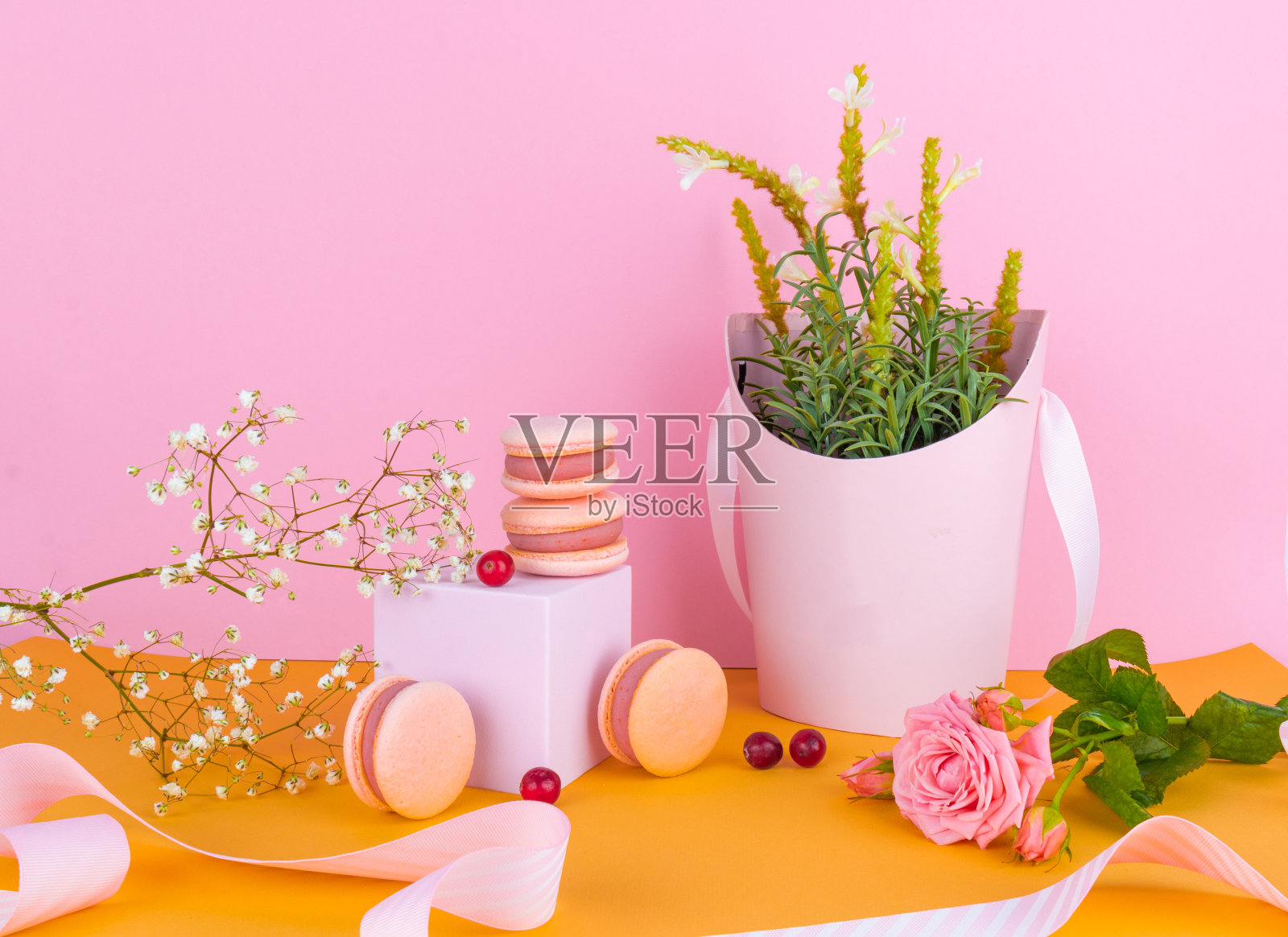粉红色的马卡龙带有浆果的味道,精致的背景与鲜花,节日的春天背景照片摄影图片