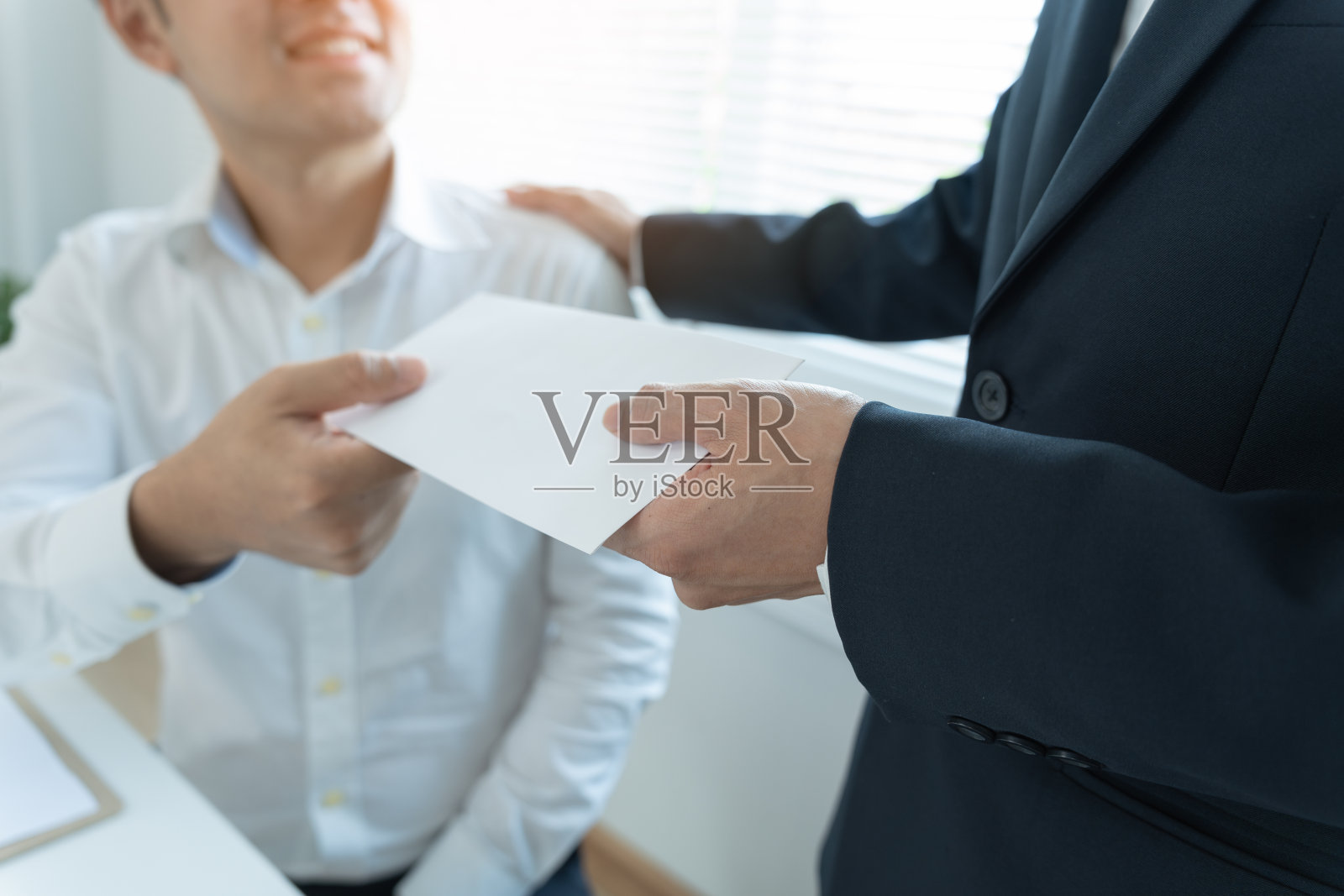 商人从管理层或老板那里获得工资或奖金。公司给予奖励以鼓励工作。微笑的商人在办公室的办公桌前享受奖励。照片摄影图片