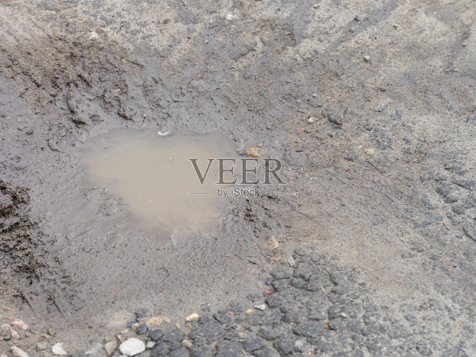 裂缝道路上泥泞的水坑的特写镜头。照片摄影图片