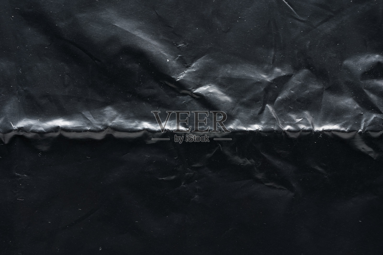 皱巴巴的黑色塑料袋质感,微距近景。照片摄影图片