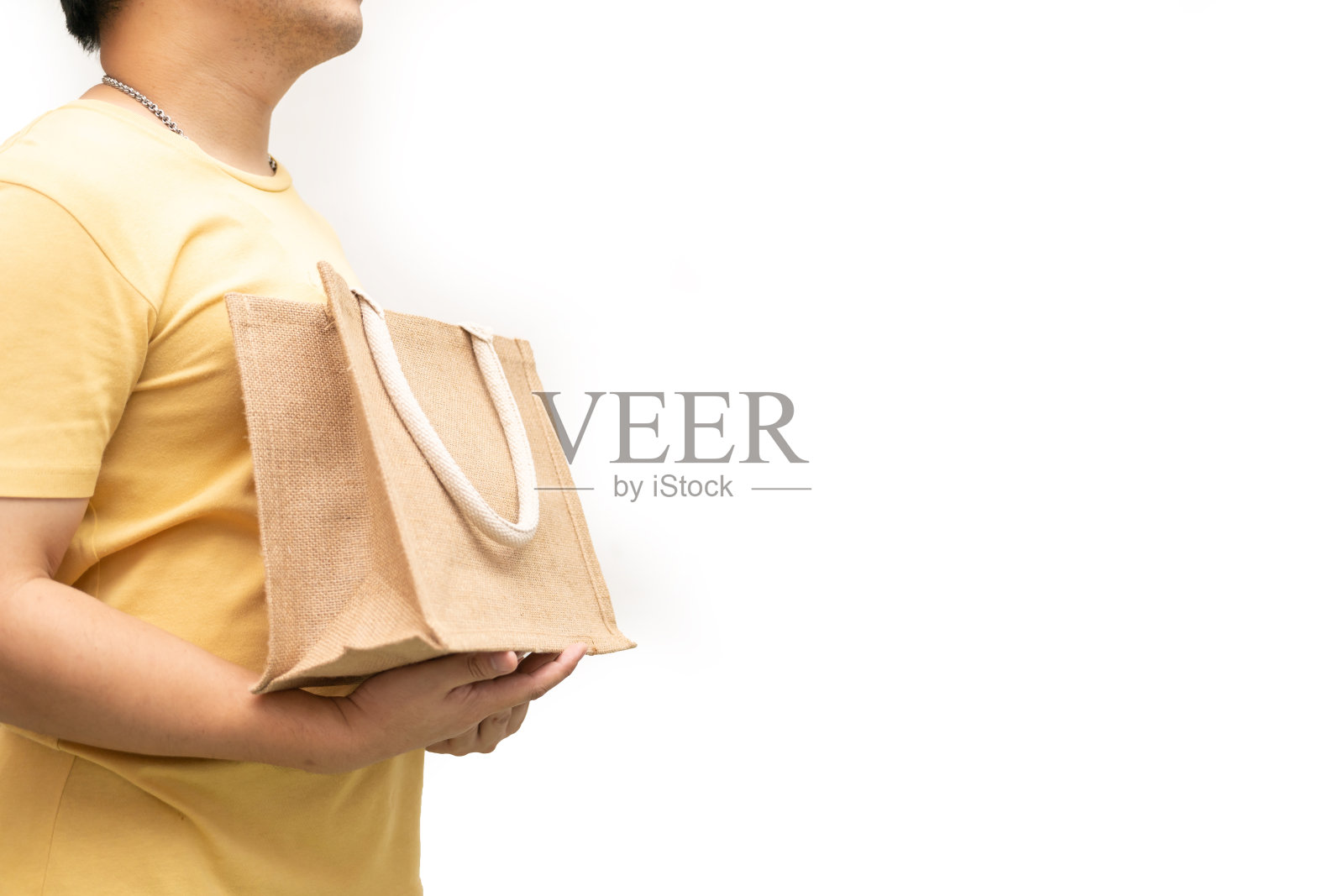 男子手持黄麻袋或麻袋在白底。可重复使用的购物袋。照片摄影图片