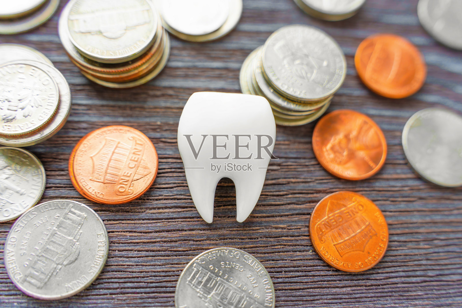 牙科费用概念:散落硬币中的牙齿模型照片摄影图片