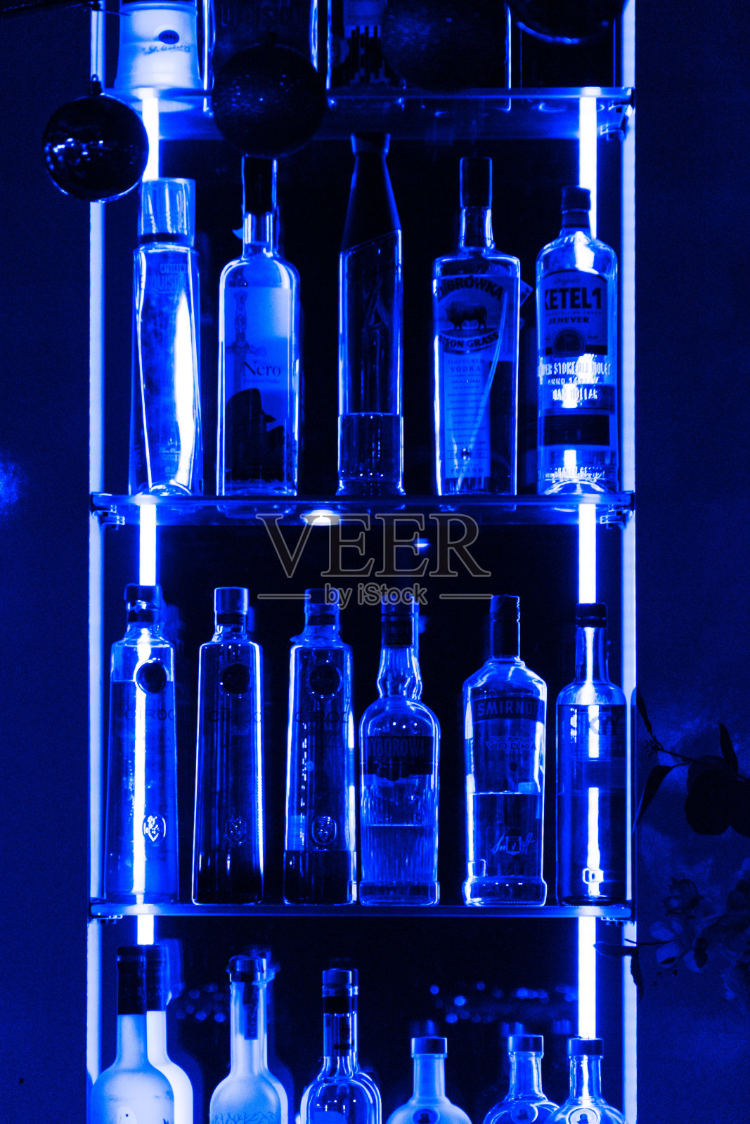 蓝色霓虹玻璃架子上的酒瓶照片摄影图片