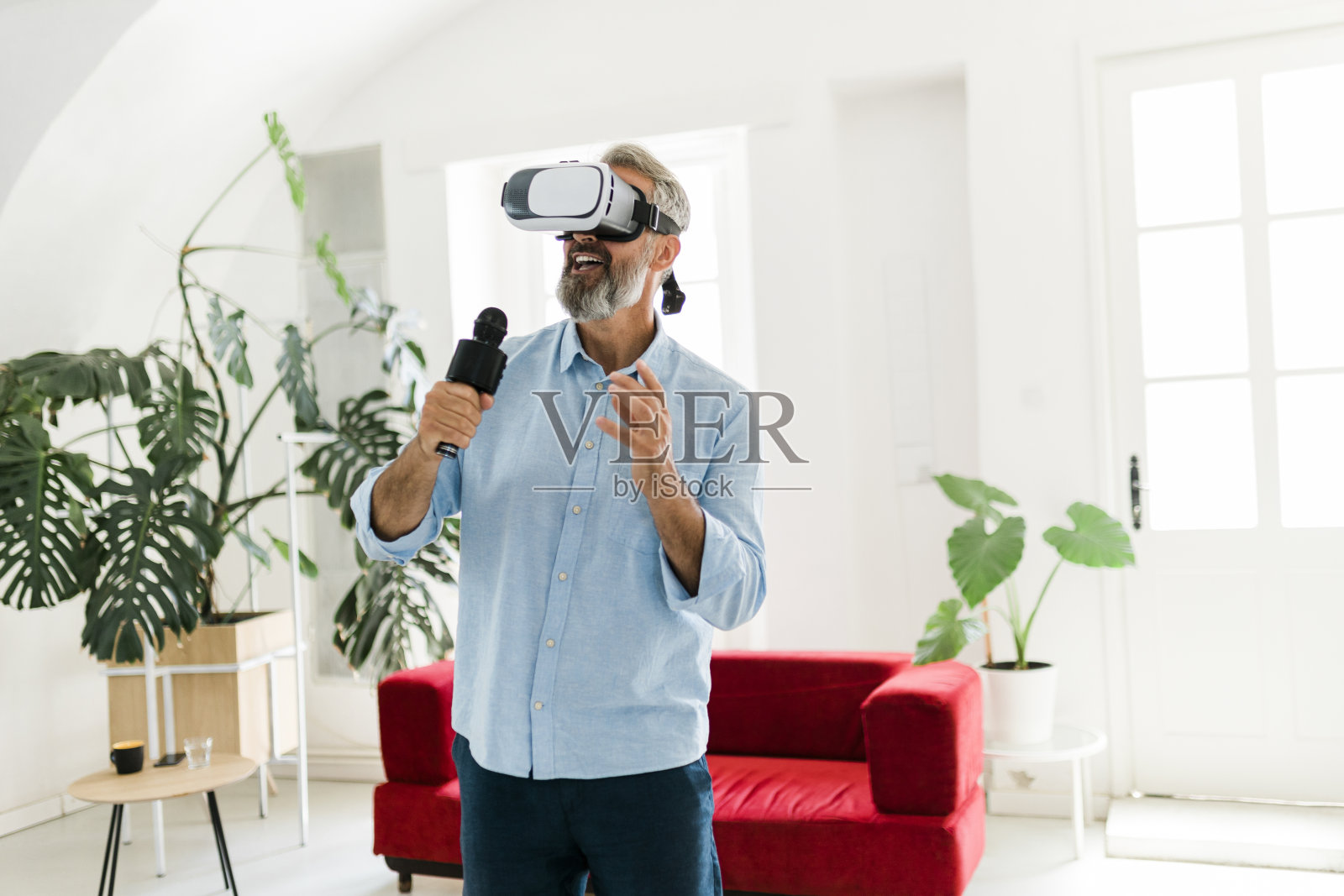 一个成熟的男人,戴着虚拟现实眼镜,一边在家听着自己喜欢的音乐,一边在卡拉ok唱歌照片摄影图片