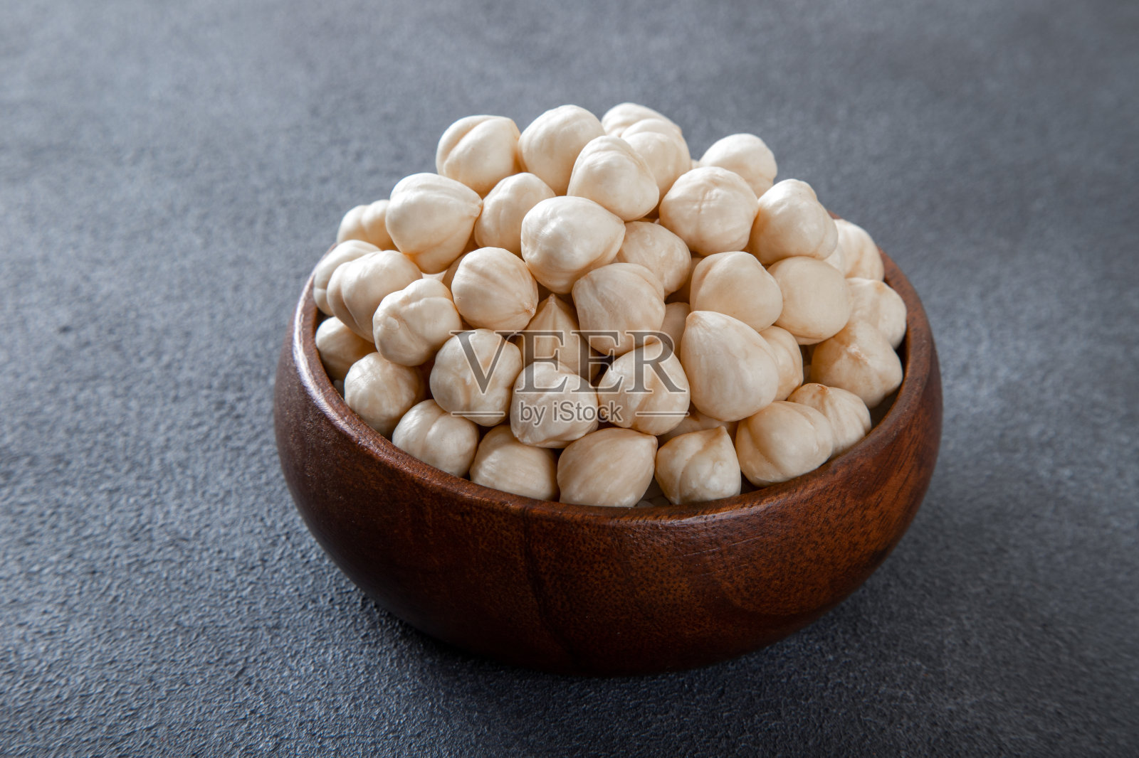 一碗去皮的榛子,黑色背景,特写照片摄影图片