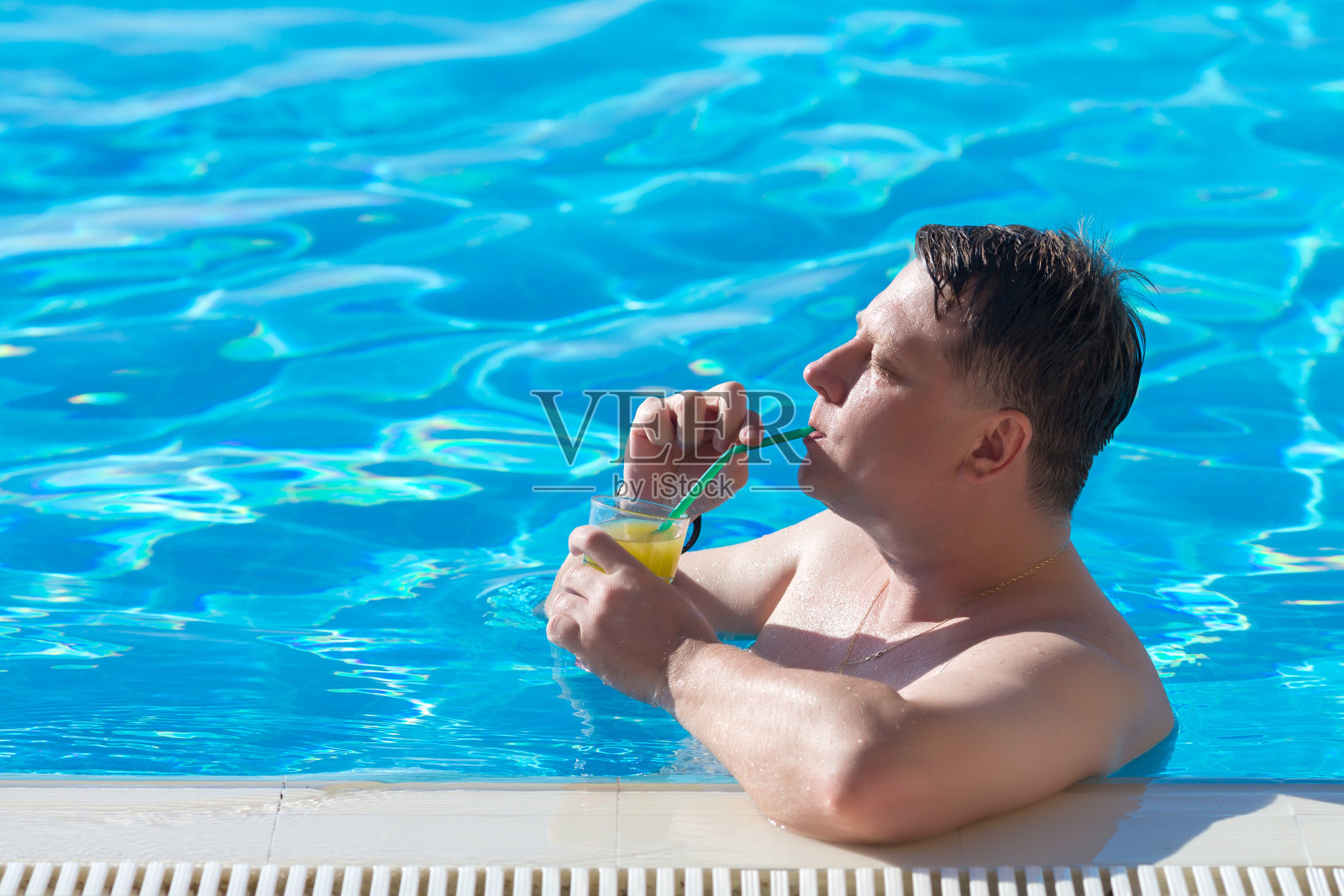 成功人士在房子附近的游泳池里喝着鸡尾酒照片摄影图片