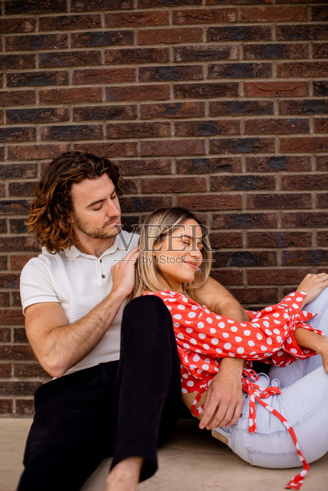 在房子砖墙前微笑相爱的年轻夫妇照片摄影图片
