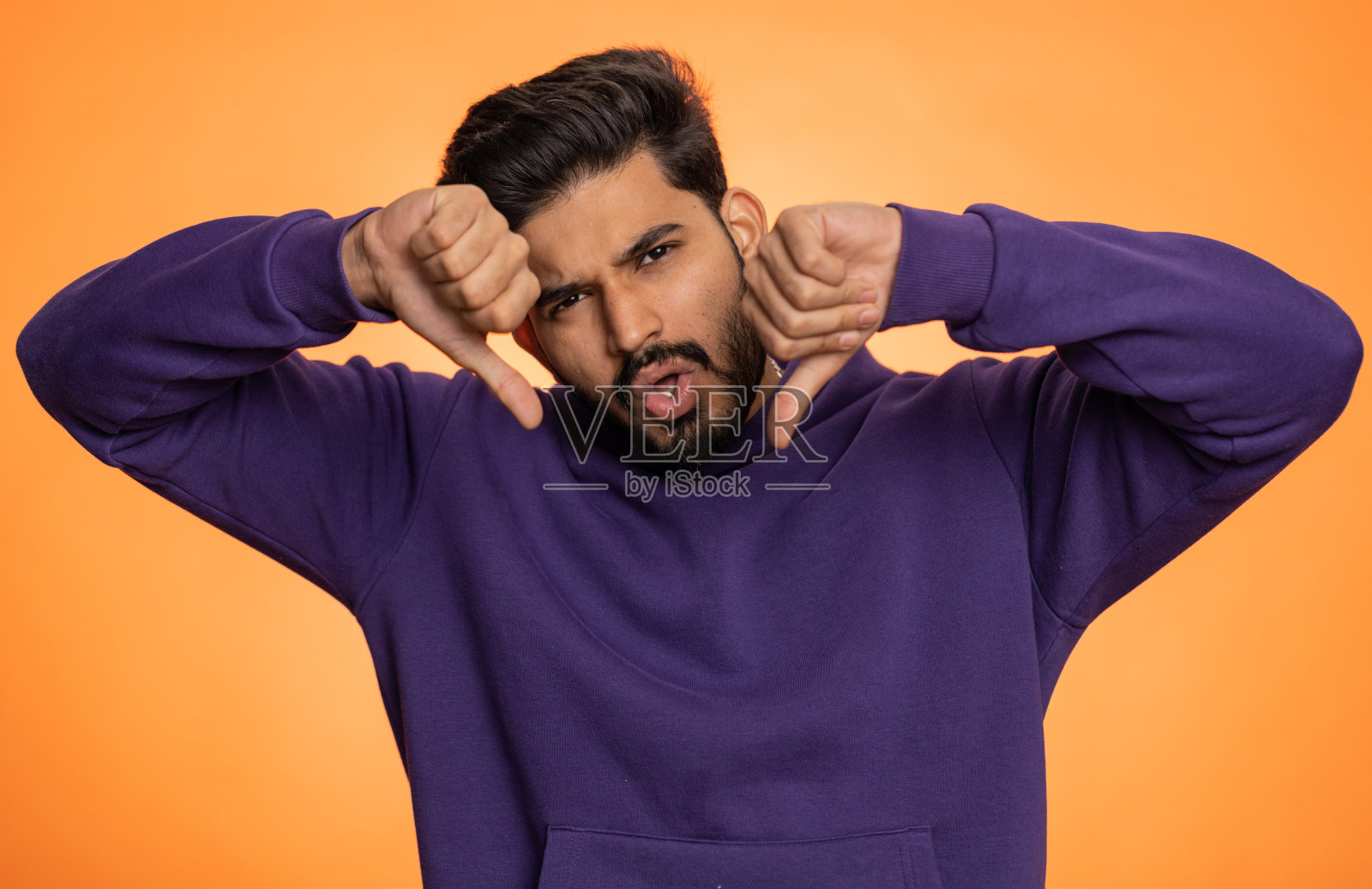 心烦意乱的帅哥穿着连帽衫,拇指朝下的手势,不赞成不满意不喜欢照片摄影图片