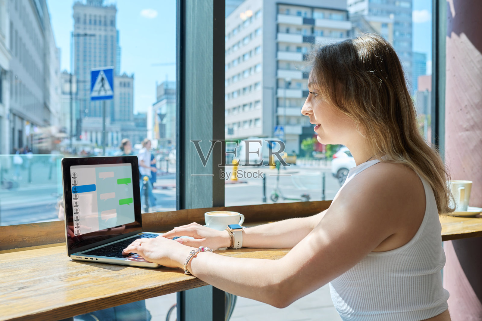 年轻的女大学生坐在咖啡馆里和朋友聊天发短信照片摄影图片