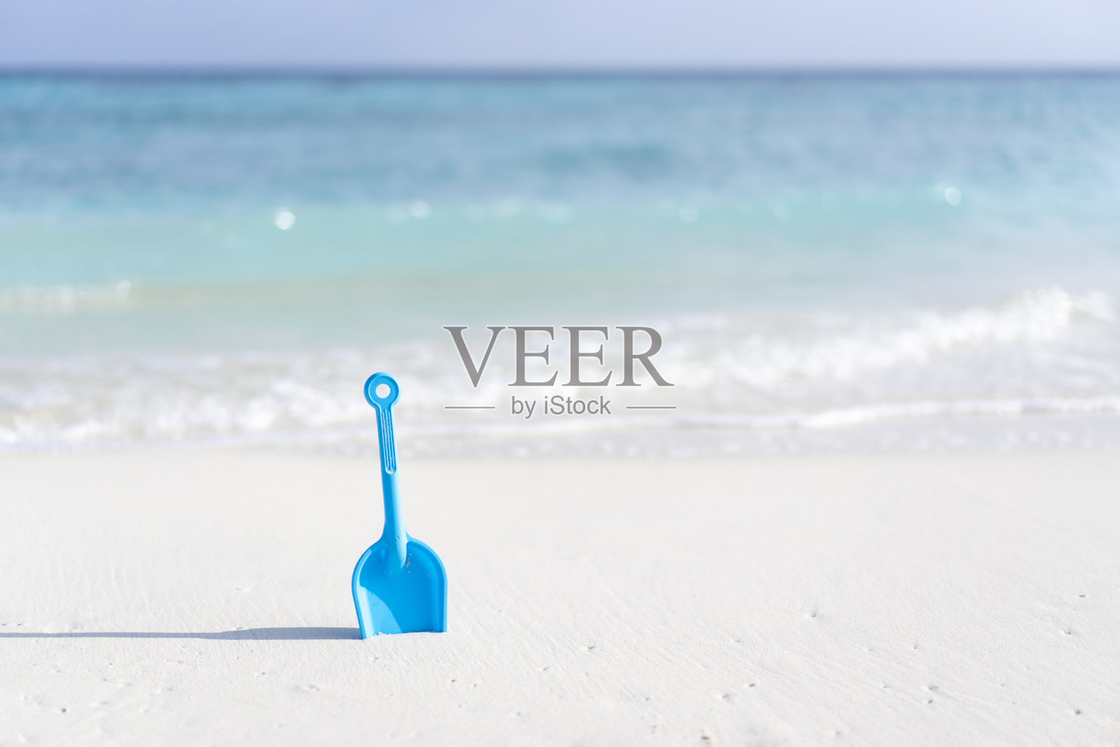 孩子们的玩具铲在沙滩上,以马尔代夫的海洋为背景。照片摄影图片