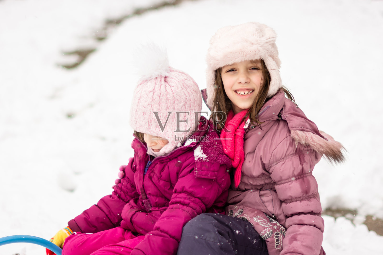 两个快乐的女孩在冬天的户外玩白色的雪橇照片摄影图片