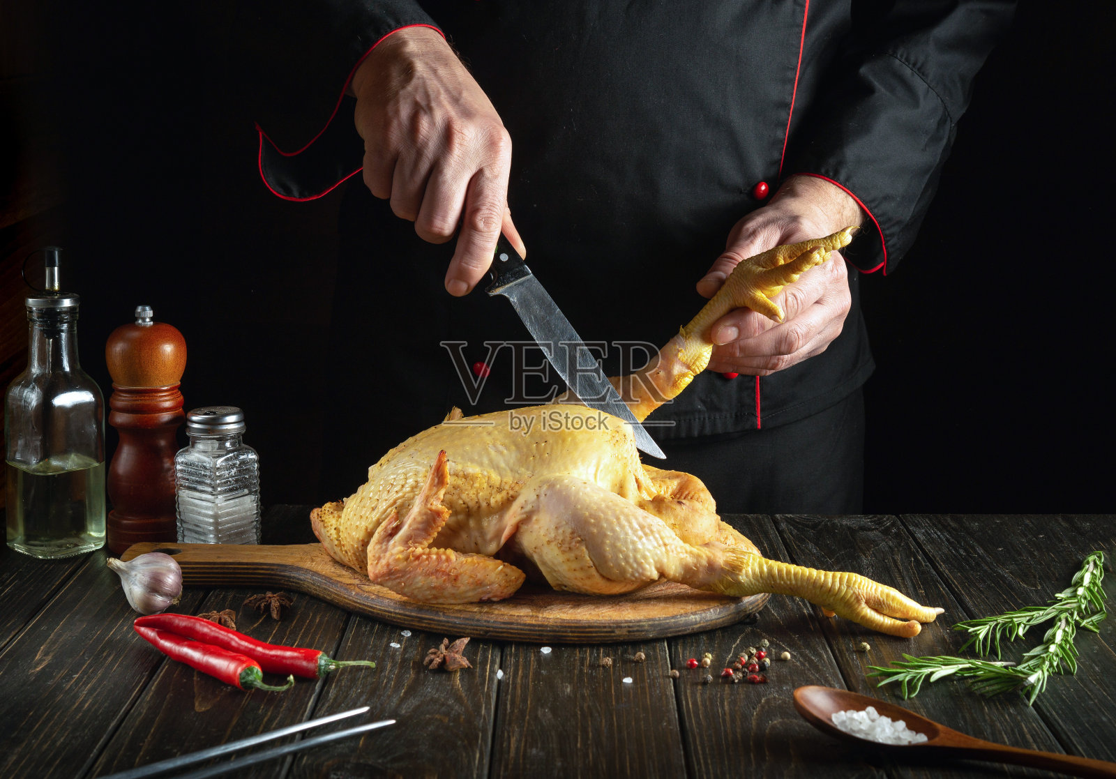 餐厅厨房里厨师亲手做的一盘炸鸡。在烹饪之前,肉鸡必须在砧板上切开。厨师手里拿着刀照片摄影图片