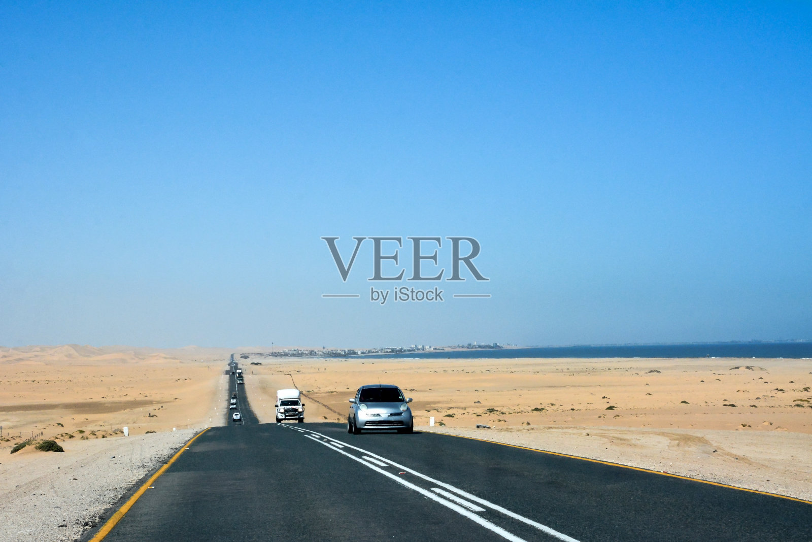 在沙漠中,各种各样的汽车沿着柏油路行驶。旅游话题与旅行照片摄影图片