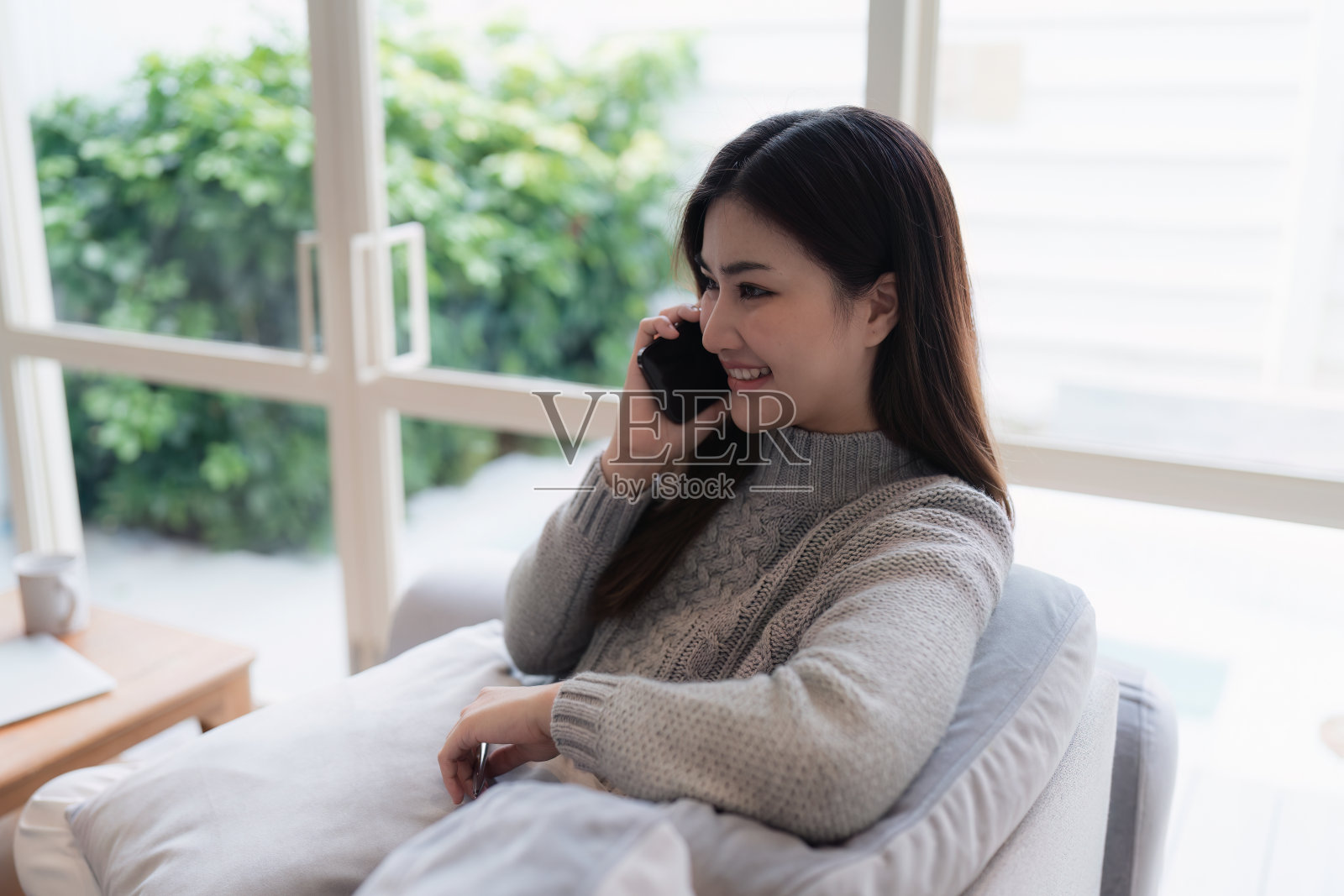 迷人的亚洲女性在舒适的客厅里休息,使用手机,放松,沙发,生活方式照片摄影图片