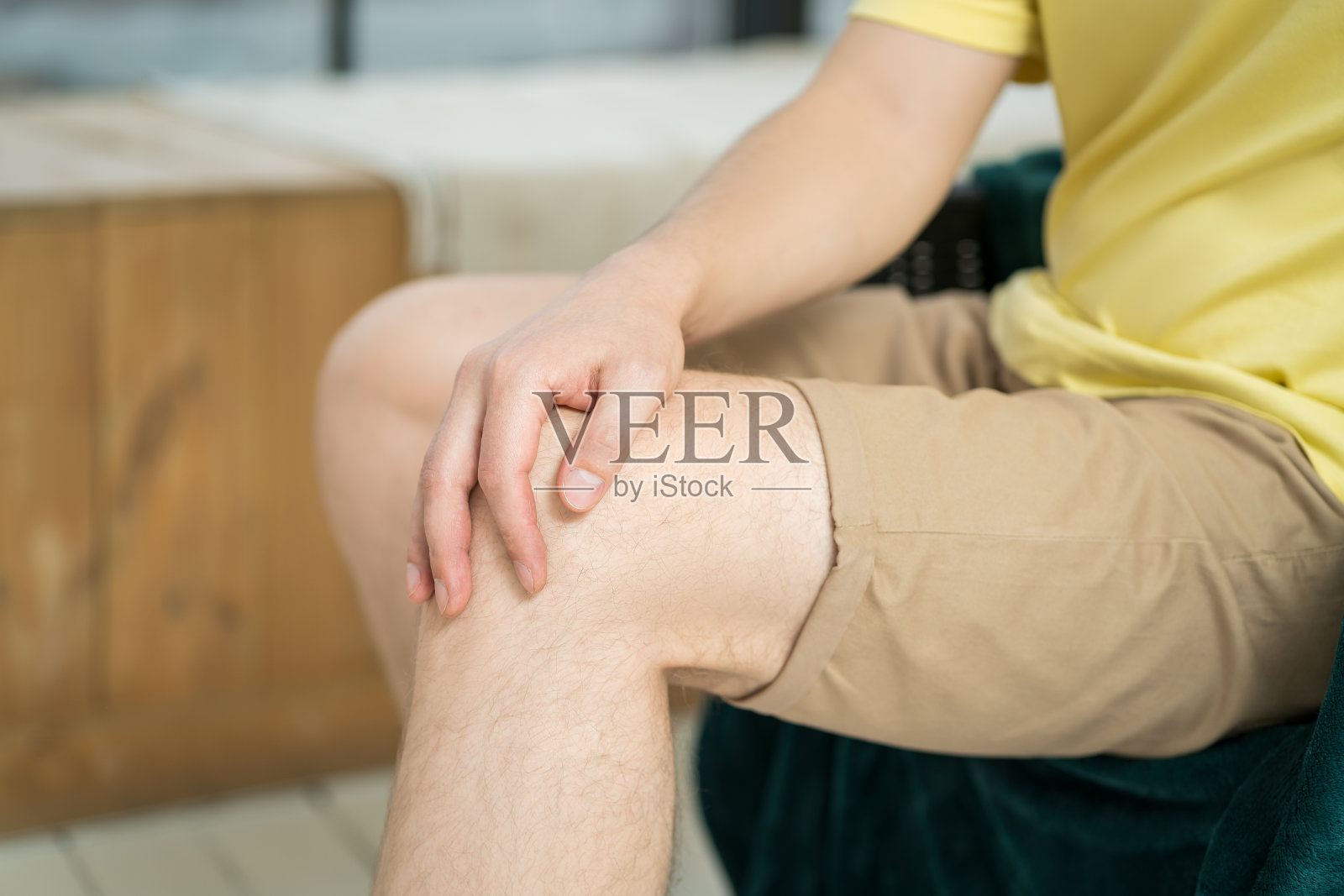膝盖疼痛,男士在家里做自我按摩照片摄影图片