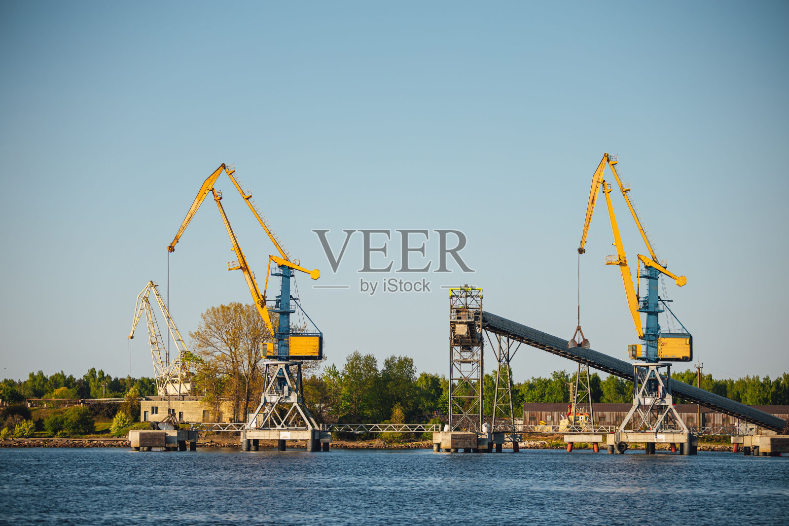 码头上有几艘船和一艘驳船,前景有一台大型起重机照片摄影图片