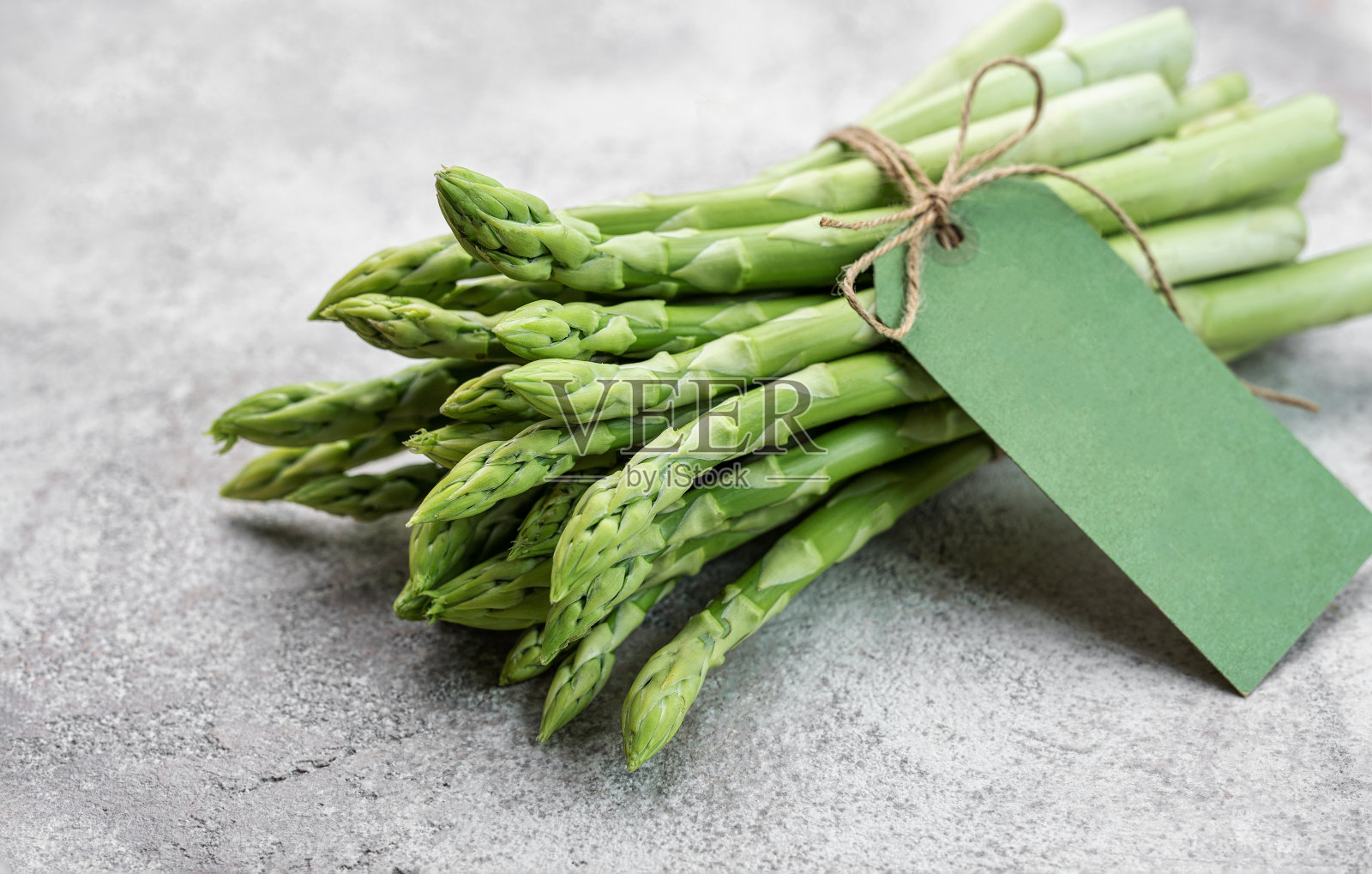 混凝土背景上的新鲜绿芦笋。照片摄影图片