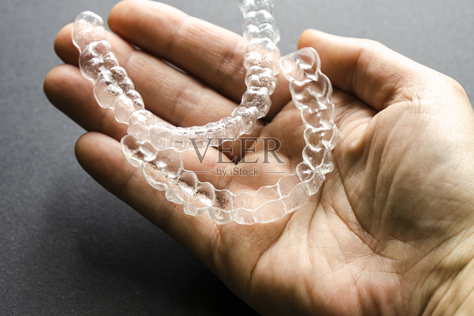 女人手里拿着两个看不见的正畸治疗照片摄影图片