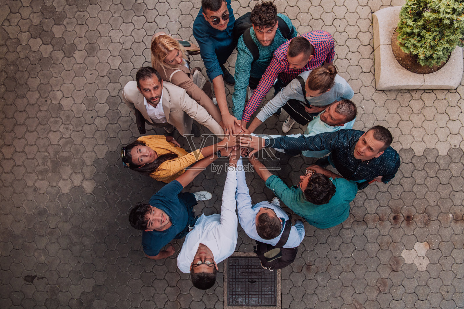 俯视图图,一群商务人士和同事手牵着手站在一起,看着镜头,象征着团结和团队精神。照片摄影图片