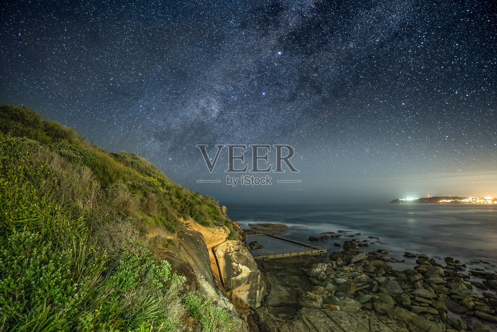 布满岩石的海岸线被夜空中明亮的星星照亮照片摄影图片