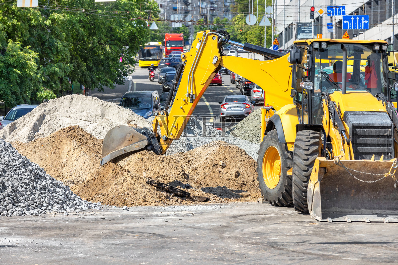 在一个阳光明媚的夏日,一辆大型建筑挖掘机的铲斗正在卸下瓦砾和沙子,背景是城市街道。副本的空间。照片摄影图片