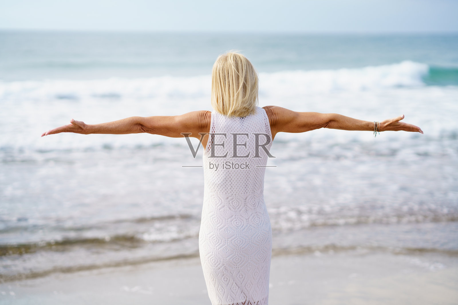 匿名的成熟女人在海边张开双臂照片摄影图片