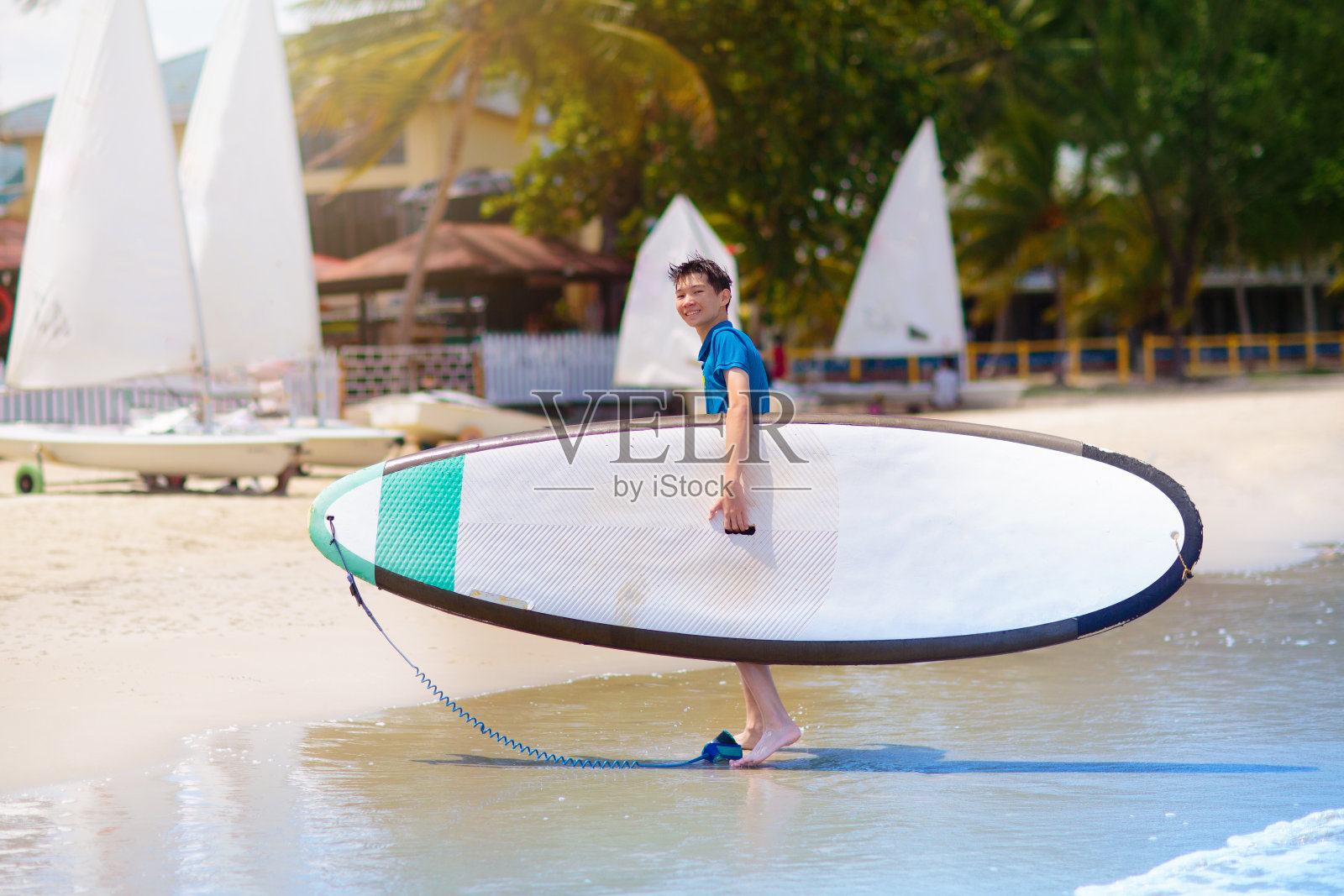孩子站起来划桨。水上和沙滩运动照片摄影图片