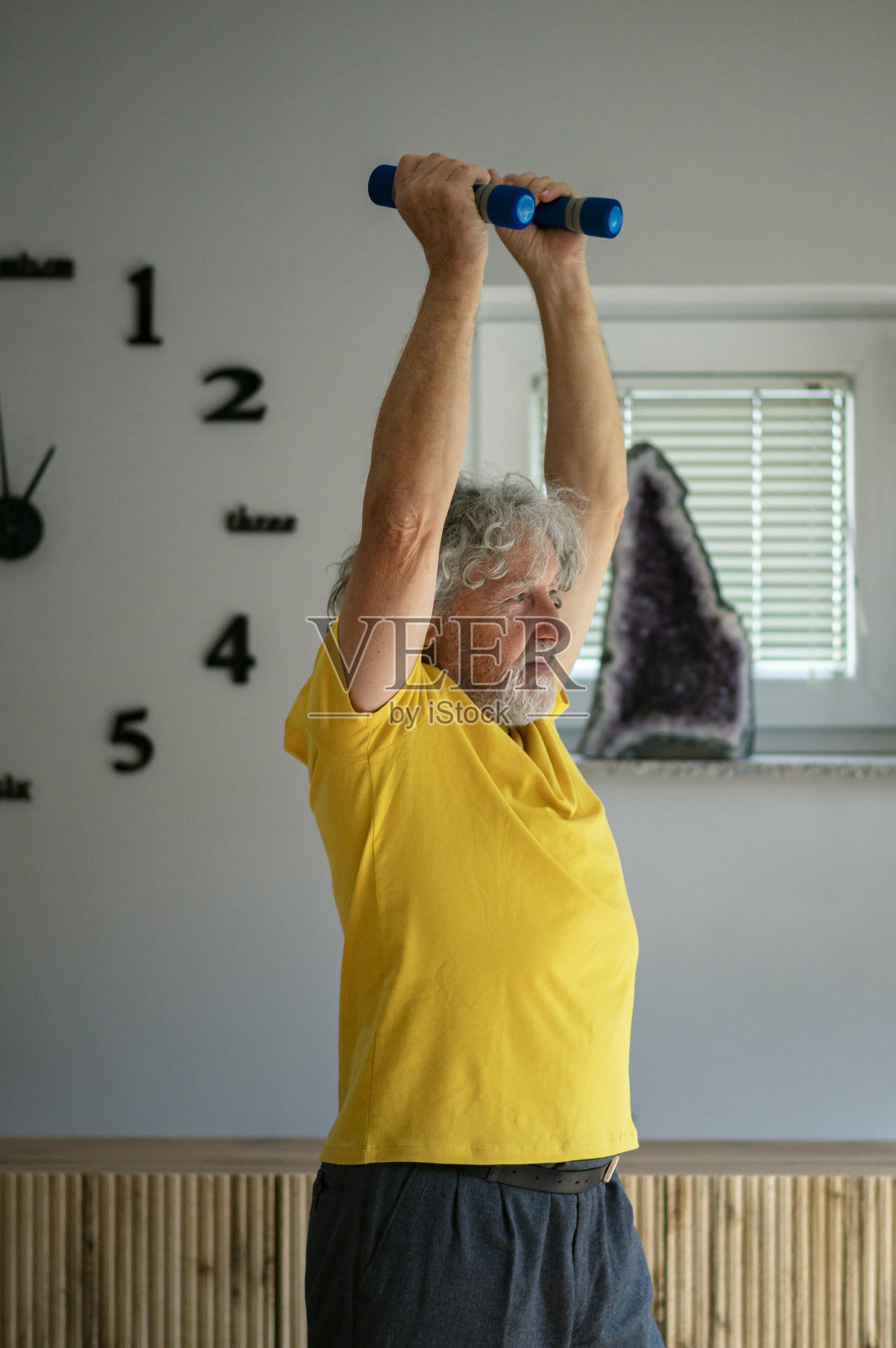 穿黄色衬衫的老人正在用哑铃举重照片摄影图片