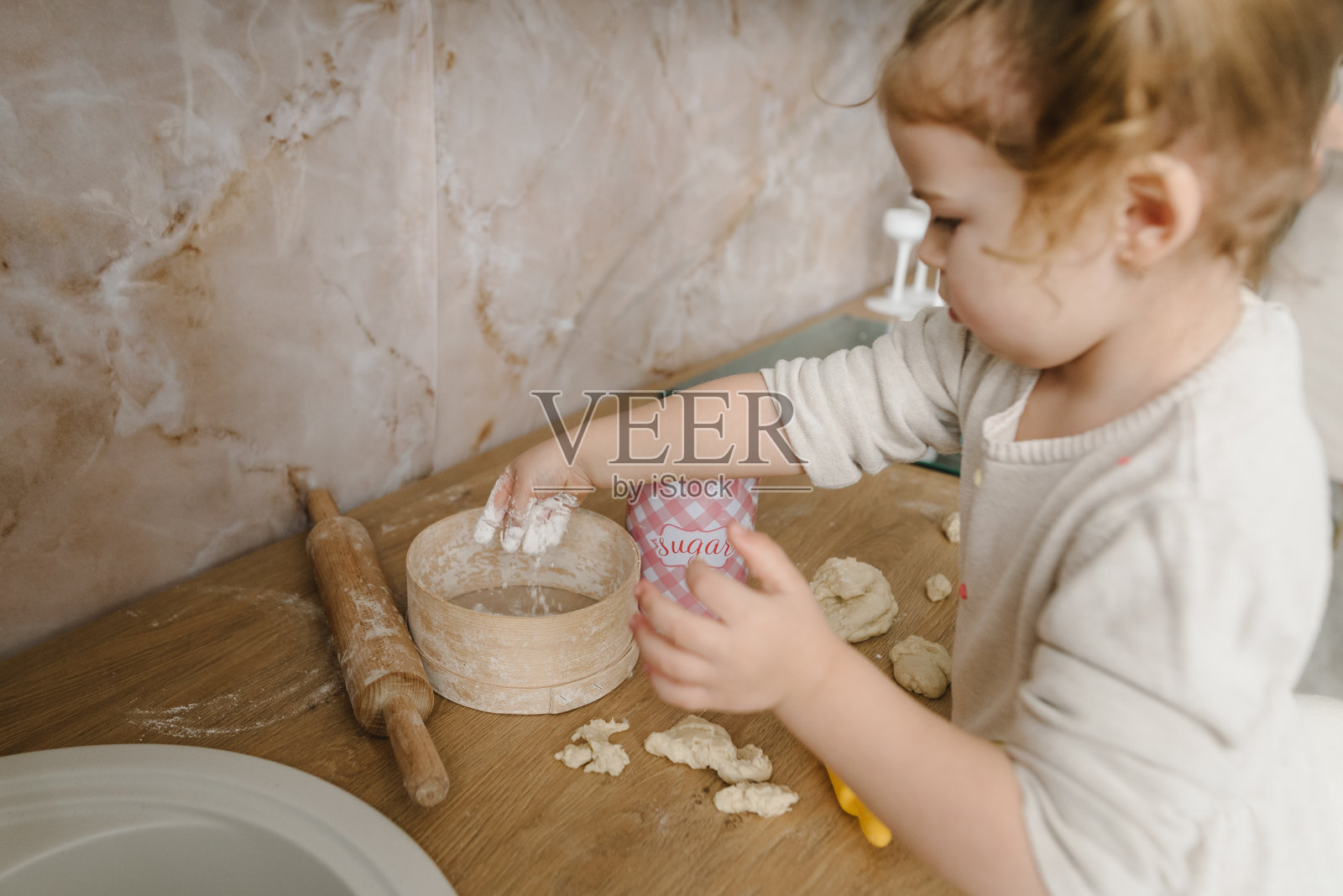 孩子给妈妈、爸爸揉面团、做披萨、烤饼干、饺子、羊角面包。小孩子女儿在厨房的桌子上做糕点或馅饼。家人在周末准备食物。照片摄影图片